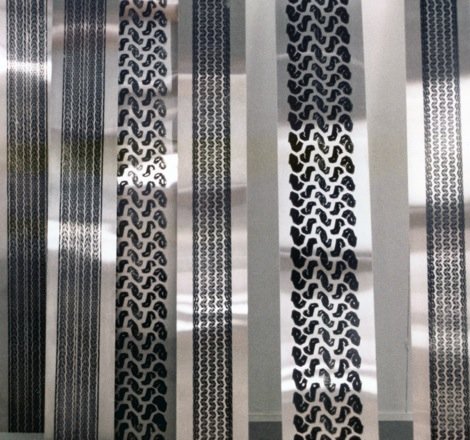 Close-up of metal strips with various perforated patterns, some with small holes and others with intricate cutouts.