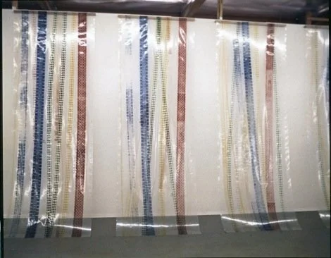 Rows of colorful woven textiles hanging in a factory or workshop.
