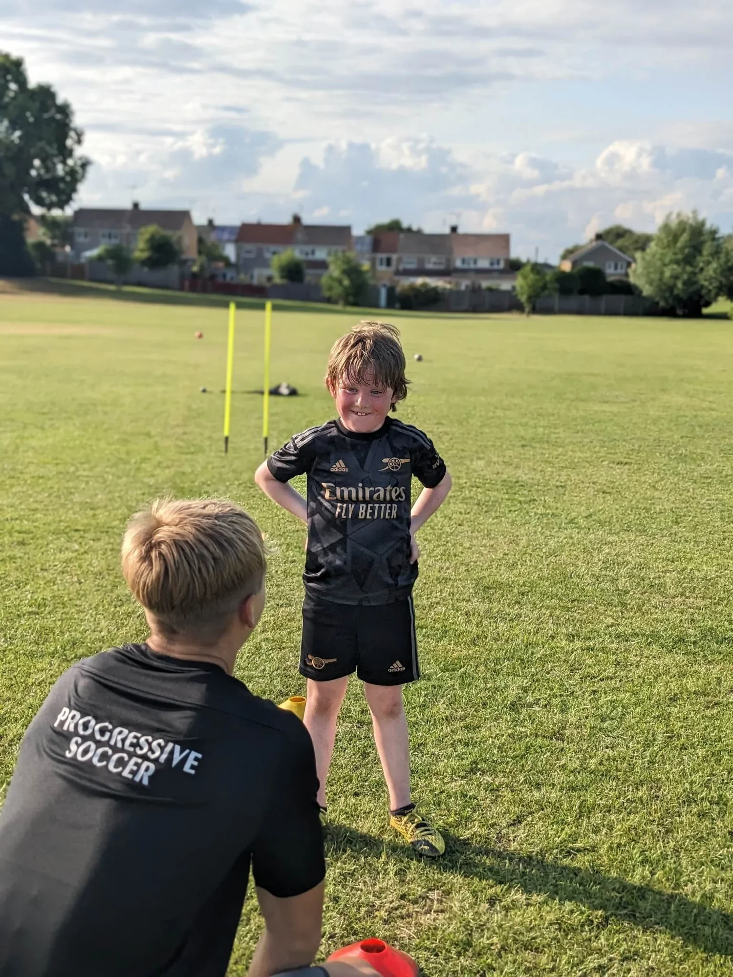 One to one football session with a smiling child and a coach dropping to the level of the child.