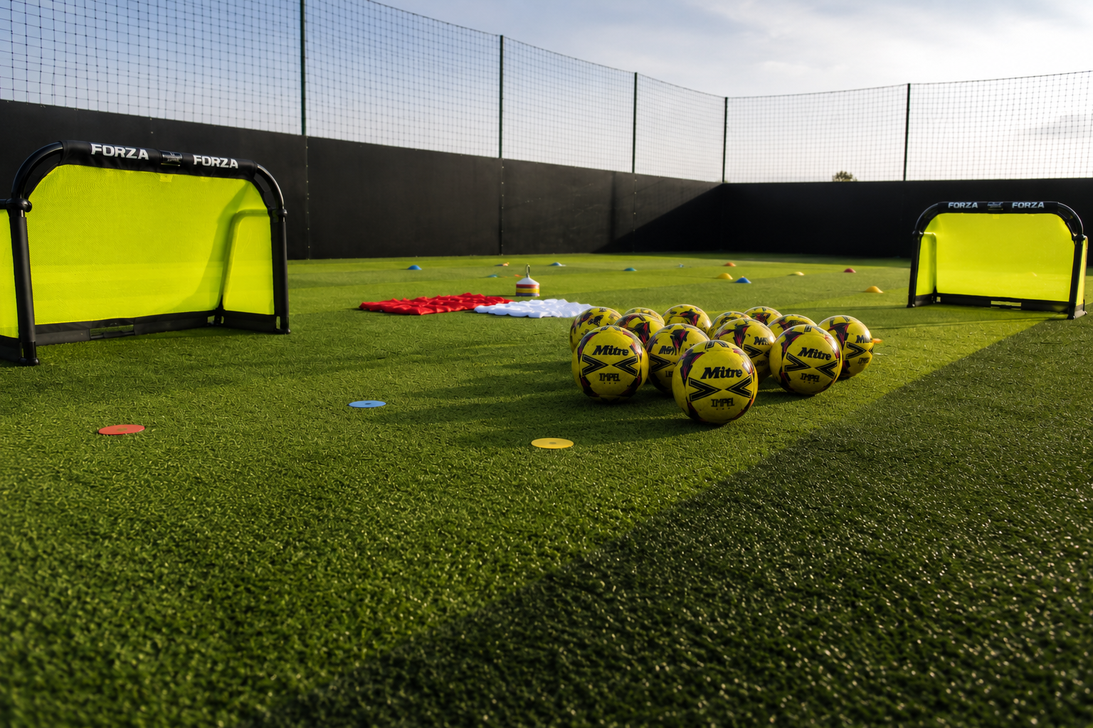 Football training equipment on artificial turf including yellow soccer balls, small goals, cones, and training tools in Bristol.