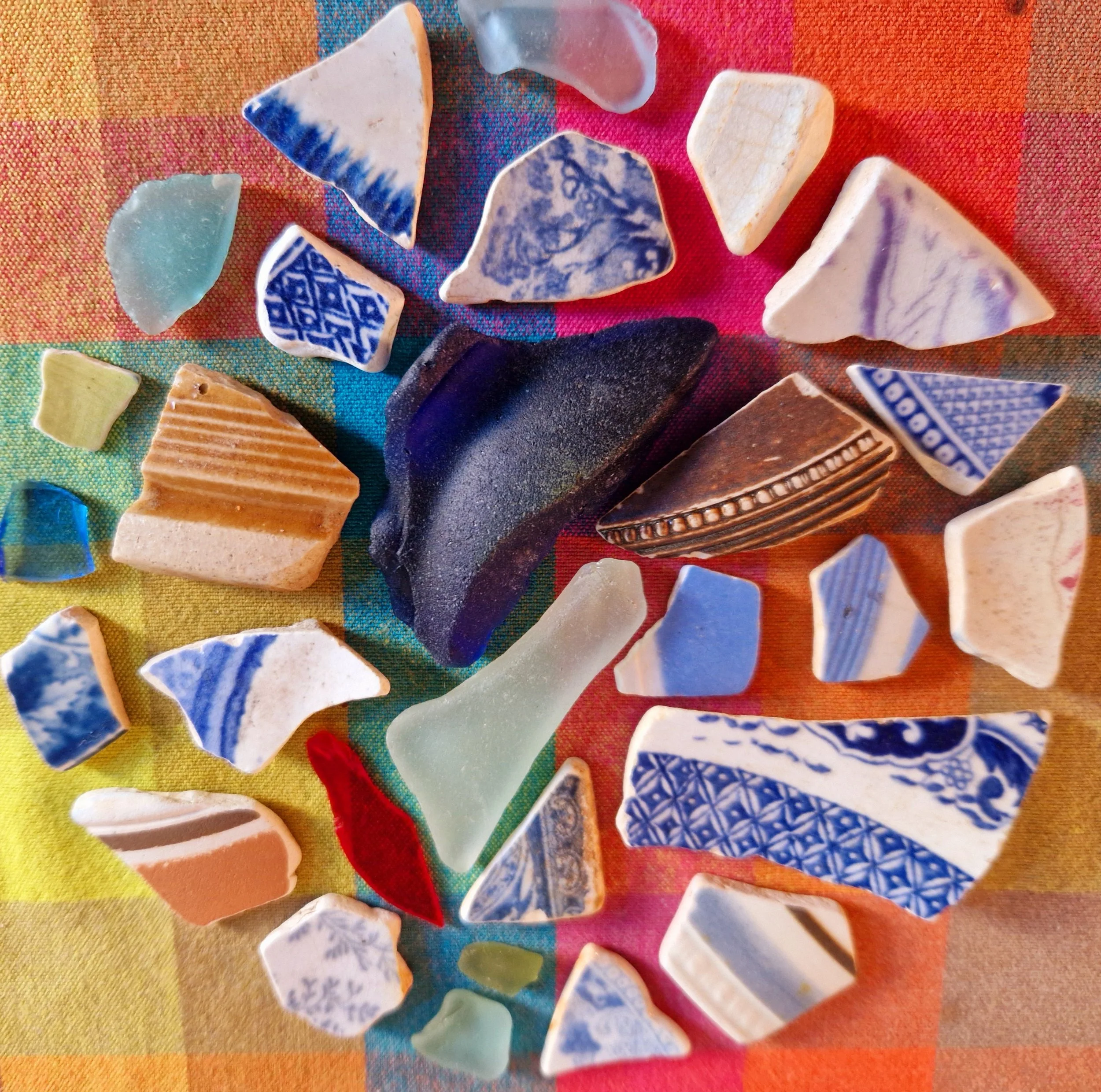 Assorted pieces of sea glass arranged on a colorful woven fabric background.