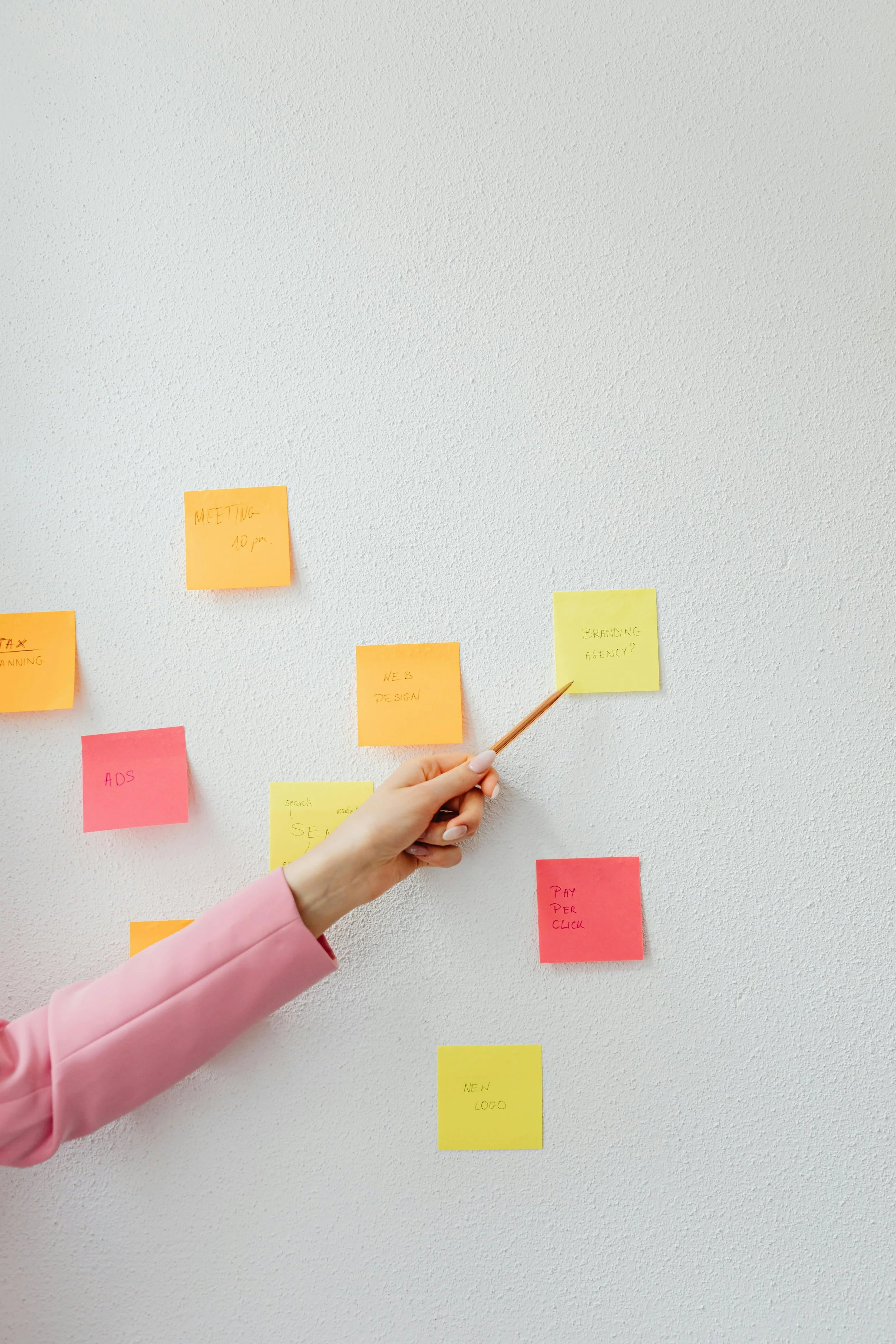 A hand points at brightly coloured sticky notes