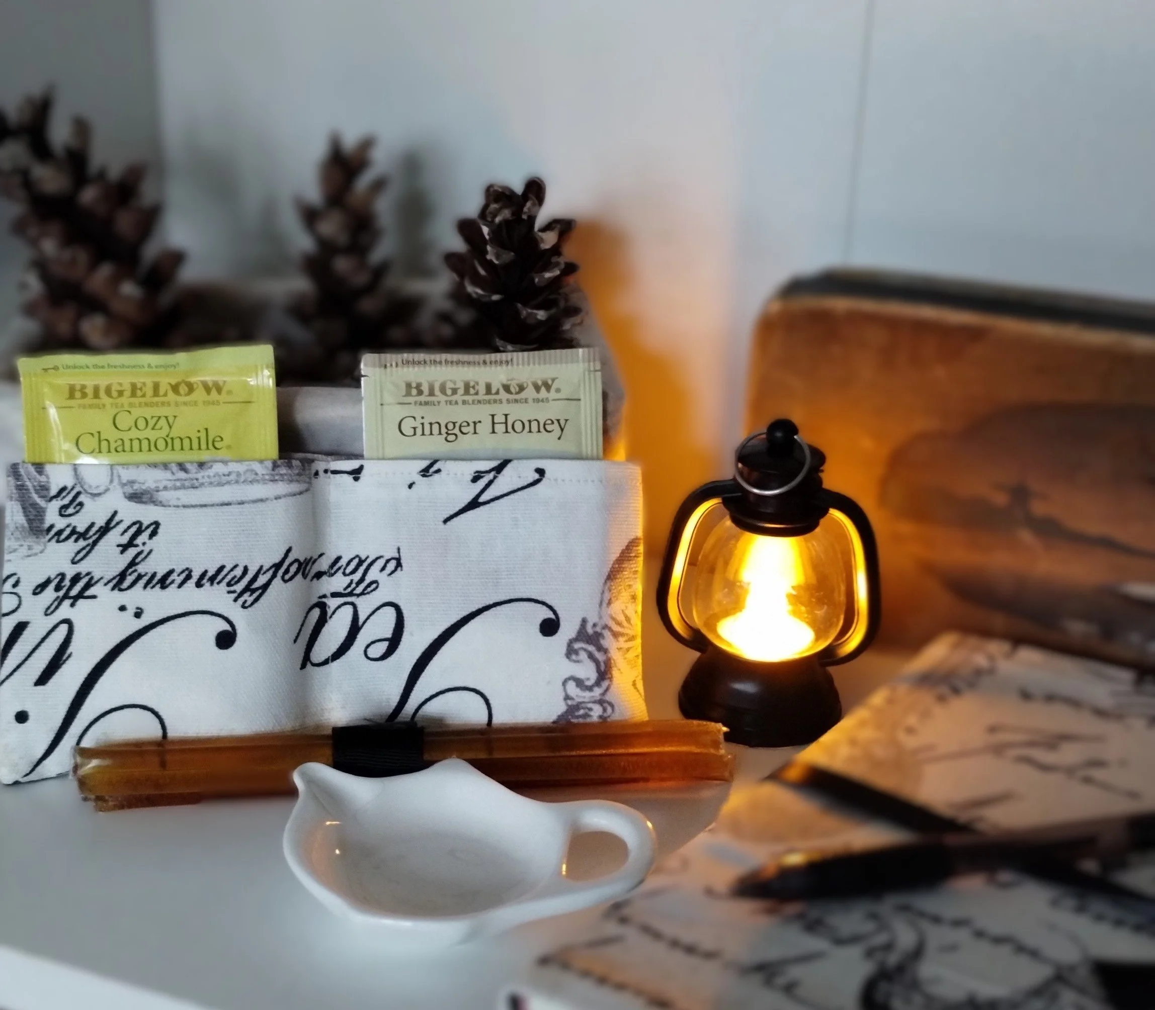Herbal tea and honey sticks displayed with a glowing mini lantern, fabric-covered journal and tea bag holder from the Cozy Evening gift set.