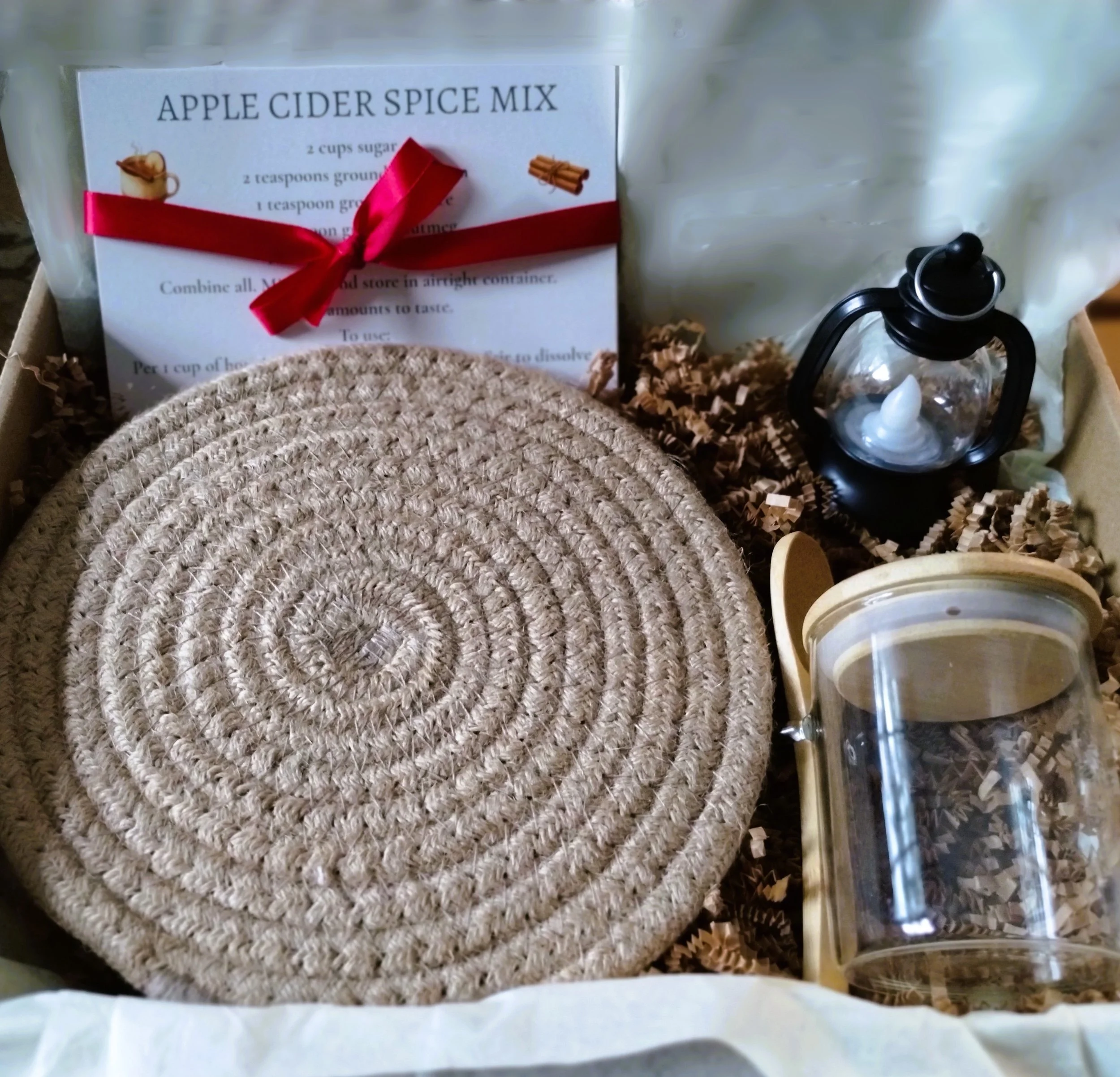 Autumn Kitchen collection in box with braided beige trivet, mini lantern, spice recipe cards, and glass spice jar with wooden lid and spoon