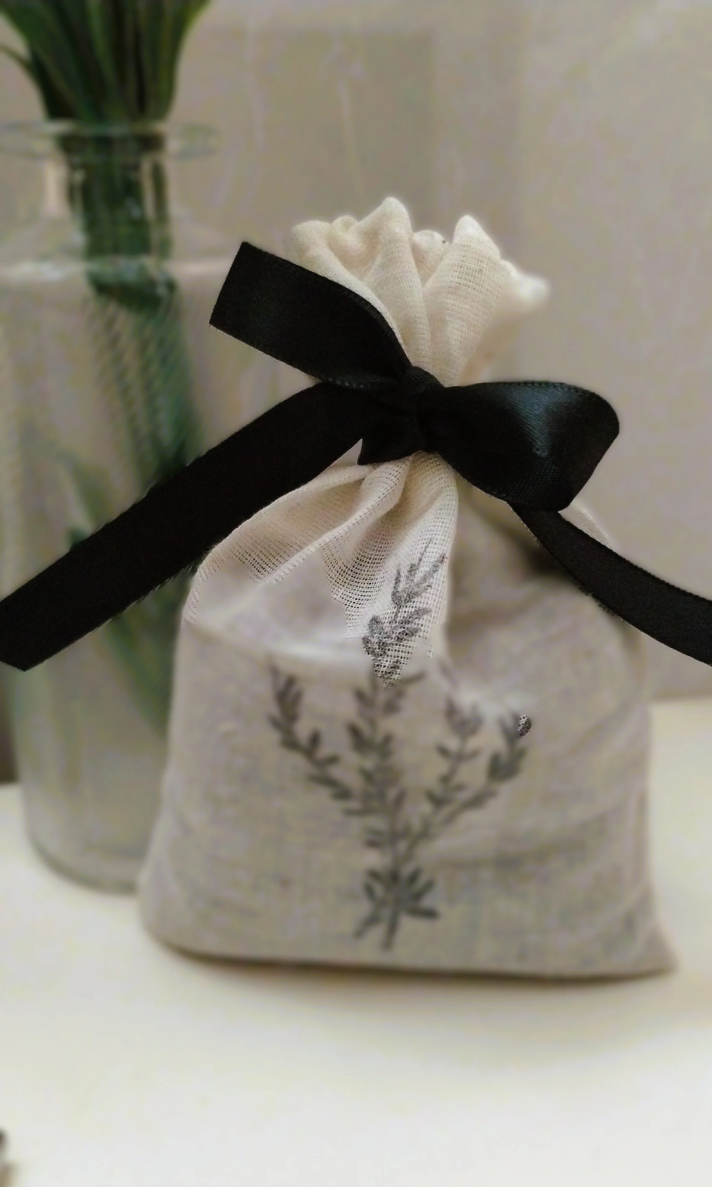 Lavender sachet in a cream botanical fabric bag finished with a black satin ribbon.