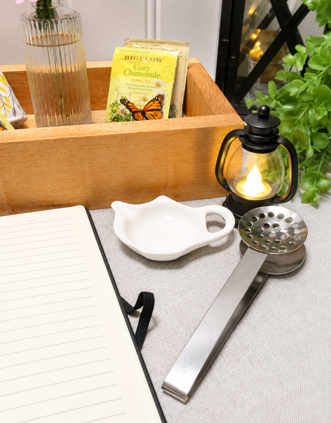 Close-up of the Evening Light Collection with handcrafted wooden tray, black lantern, honey dish, tea infuser, notebook, and tea.