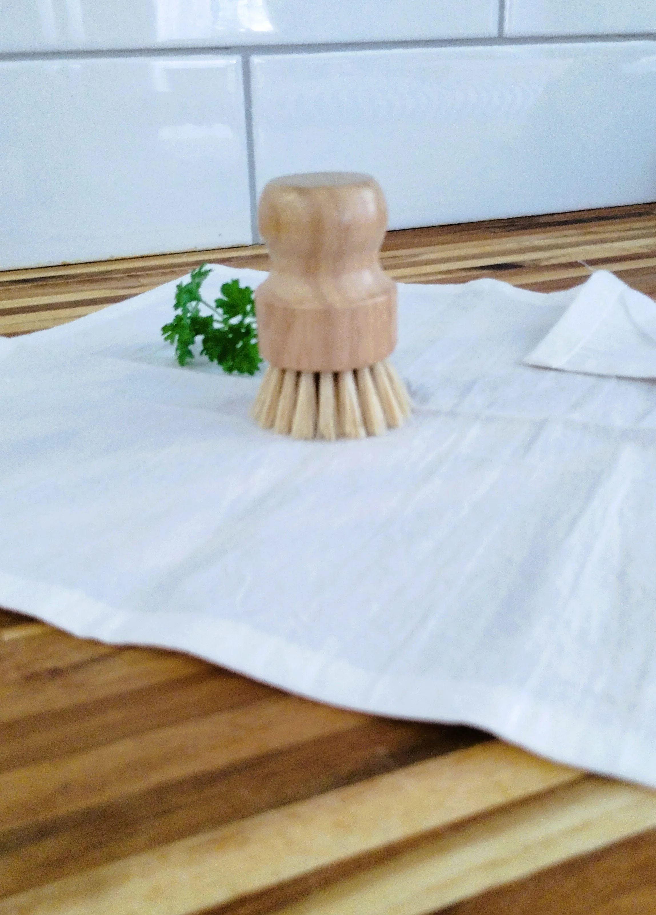 Natural bristle produce scrubber resting on a handmade white produce cloth.