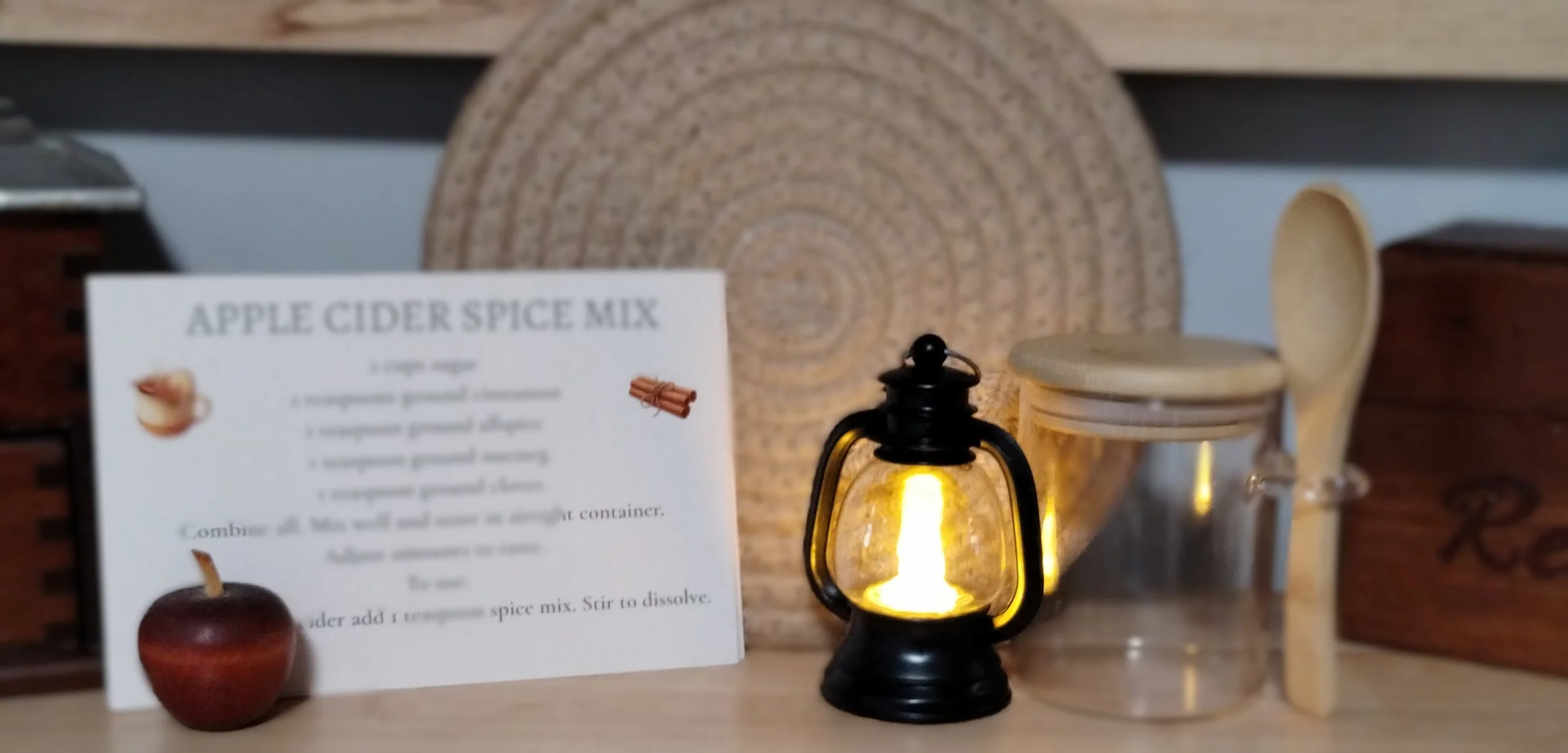 Autumn Kitchen collection featuring beige braided trivet, glowing mini lantern, spice recipe cards and glass spice jar with wooden lid and spoon