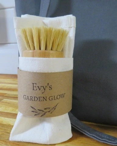 Natural produce brush wrapped in a reusable cotton produce cloth with Evy's Garden Glow band.