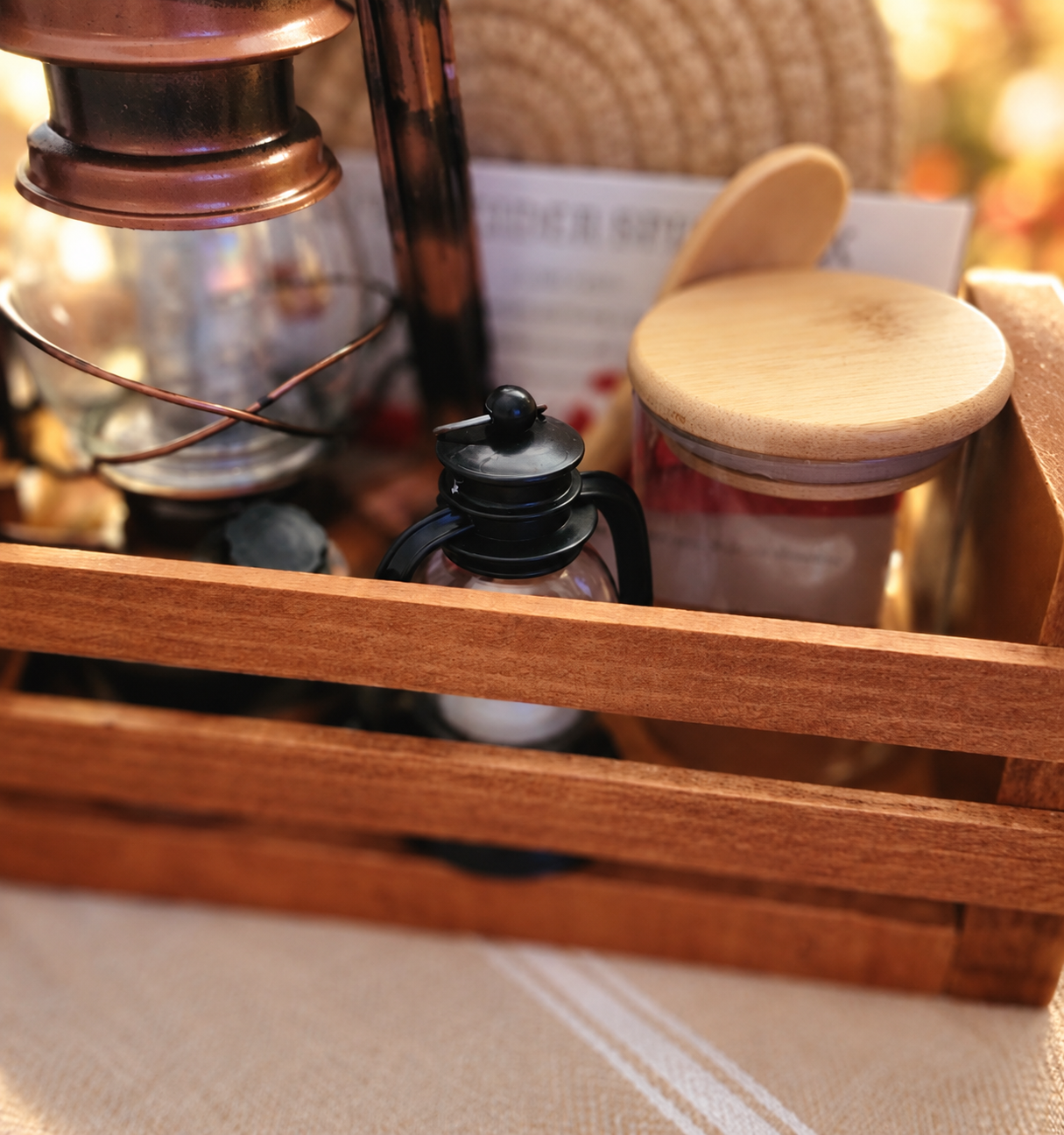 Close-up of the Autumn Evening Collection's handcrafted wooden crate holding a copper lantern, miniature black lantern, glass jar with wooden lid, wooden spoon, and seasonal spice recipe cards.