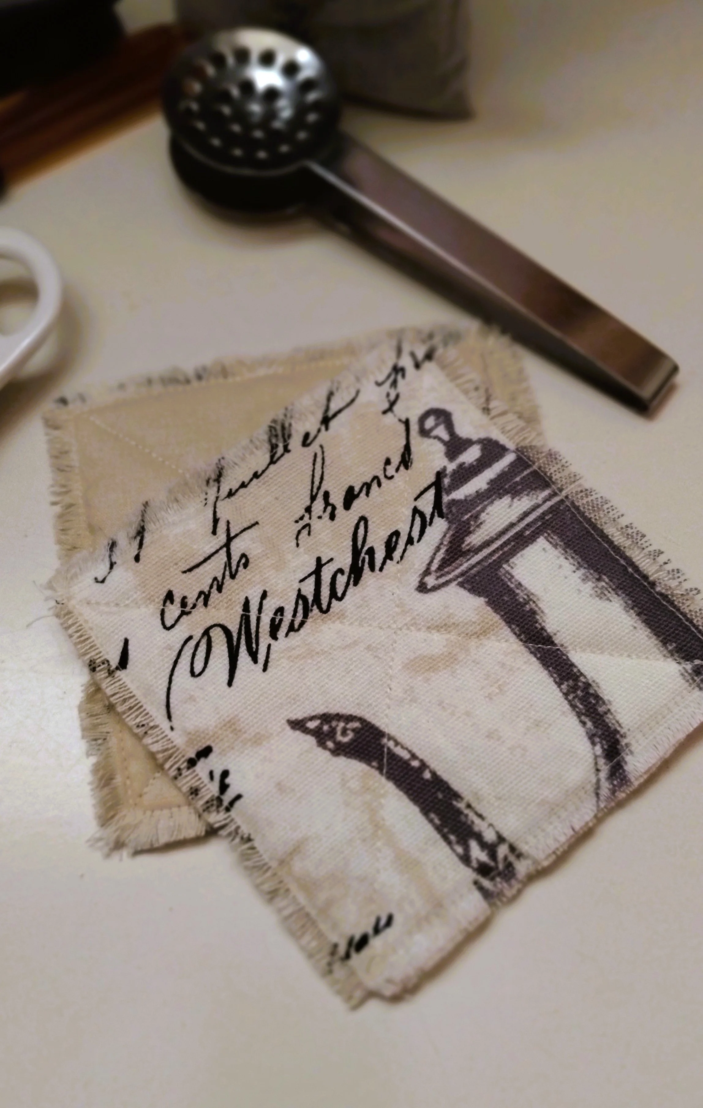 Handmade black and cream fabric coasters with frayed edges and vintage script design.