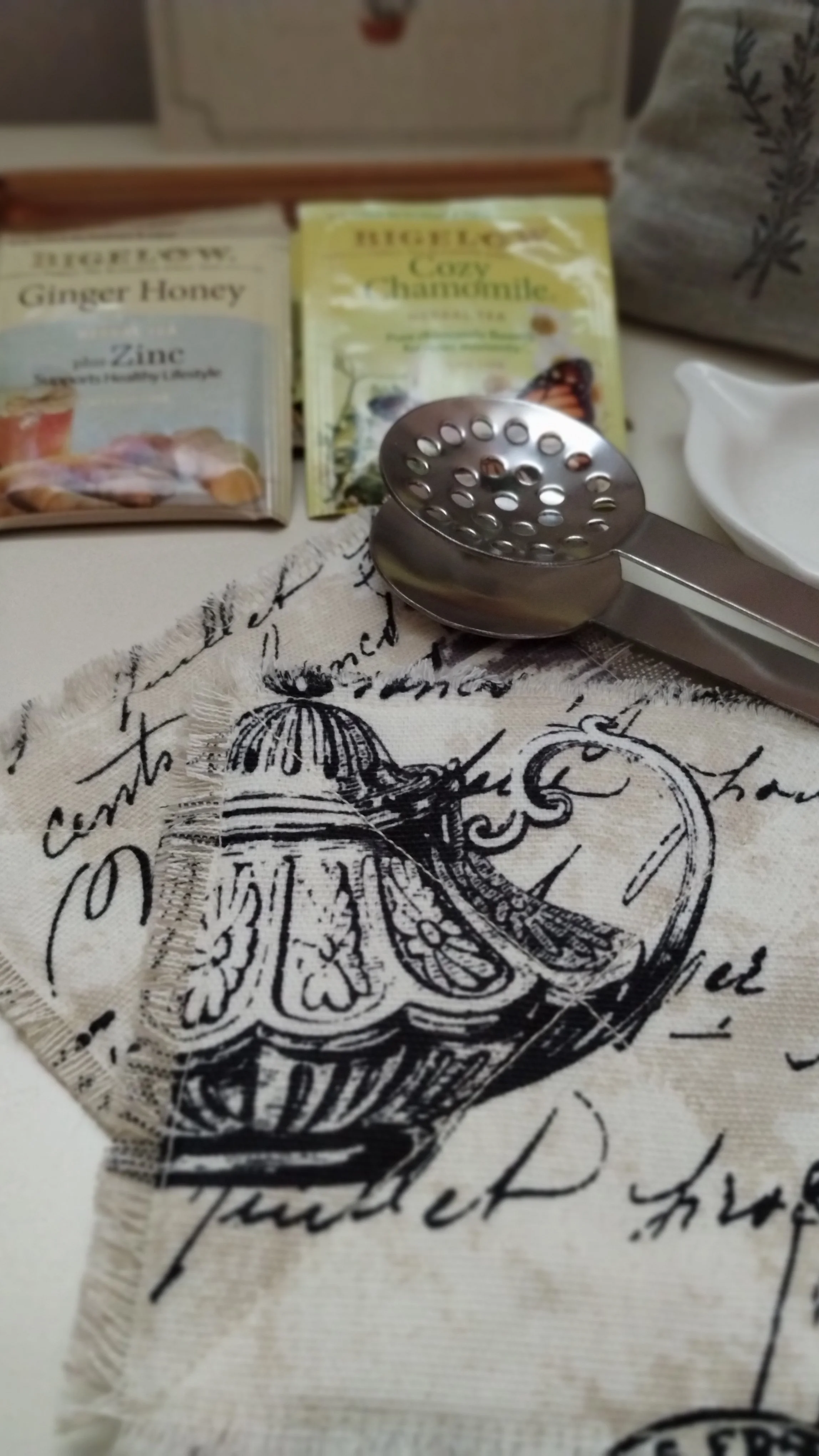 Tea bag squeezer displayed with handmade frayed fabric coasters and herbal tea.