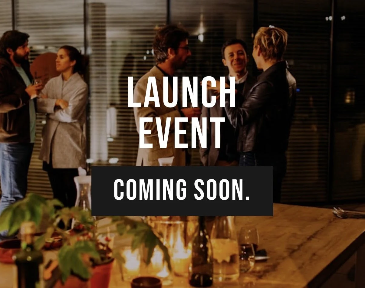 Group of people socializing at a launch event in a warmly lit room with a table decorated with candles and plants.