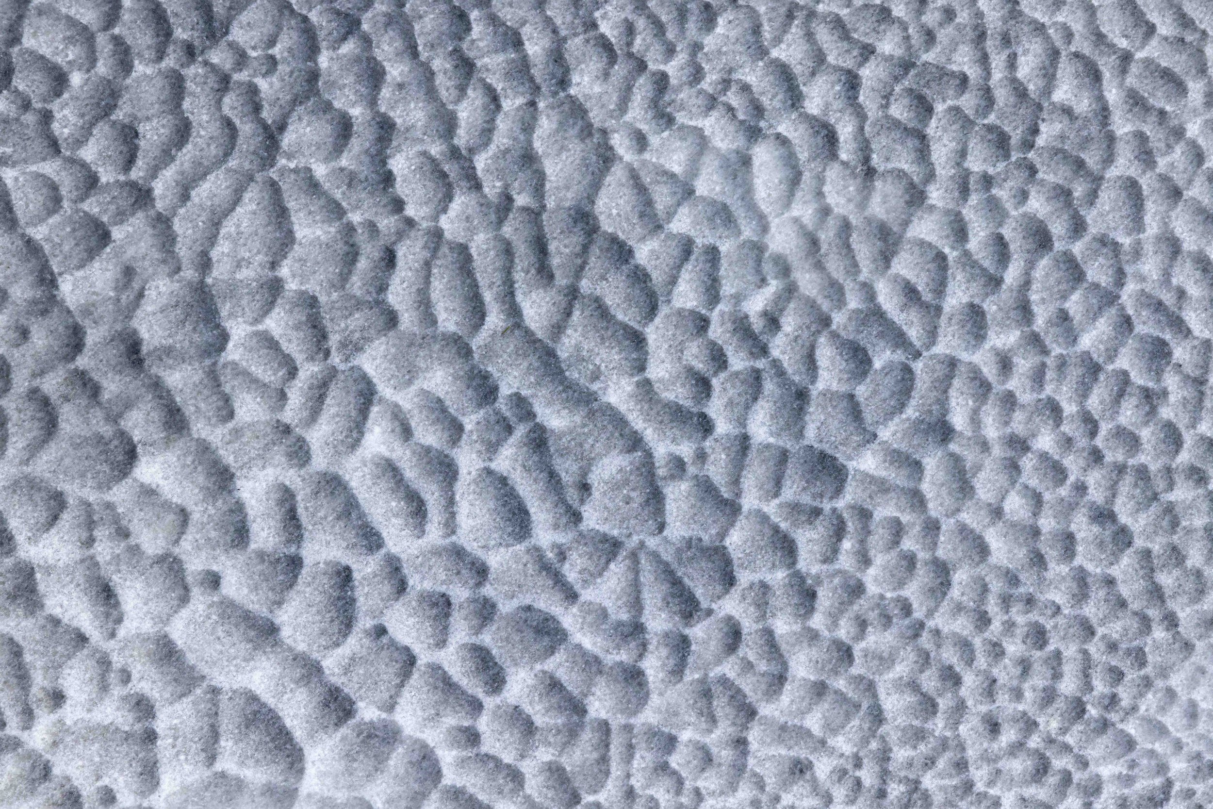 Fotografía minimalista de textura de marmol, con endiduras y relieves marcados.