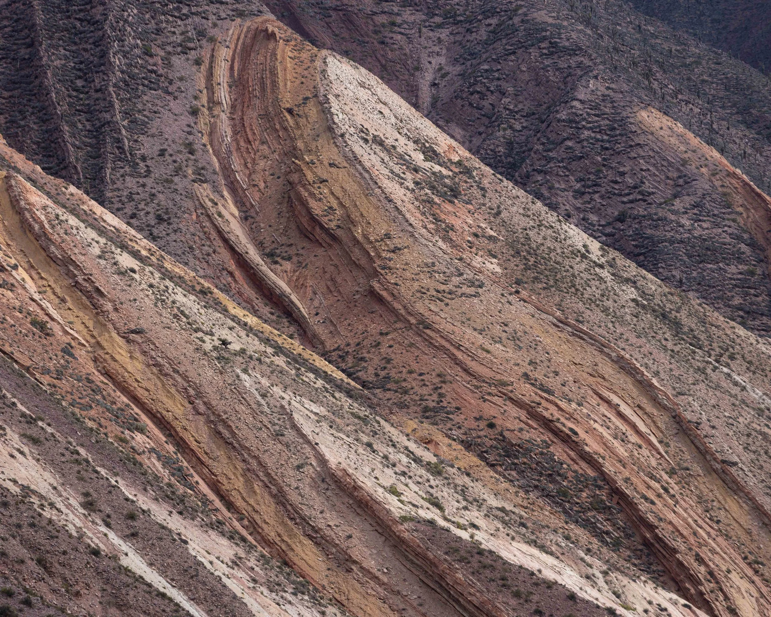 Paisaje geológico de Maimará, Jujuy, en el norte de Argentina, con montañas áridas, texturas naturales y capas de colores que revelan la belleza mineral de la Quebrada de Humahuaca.