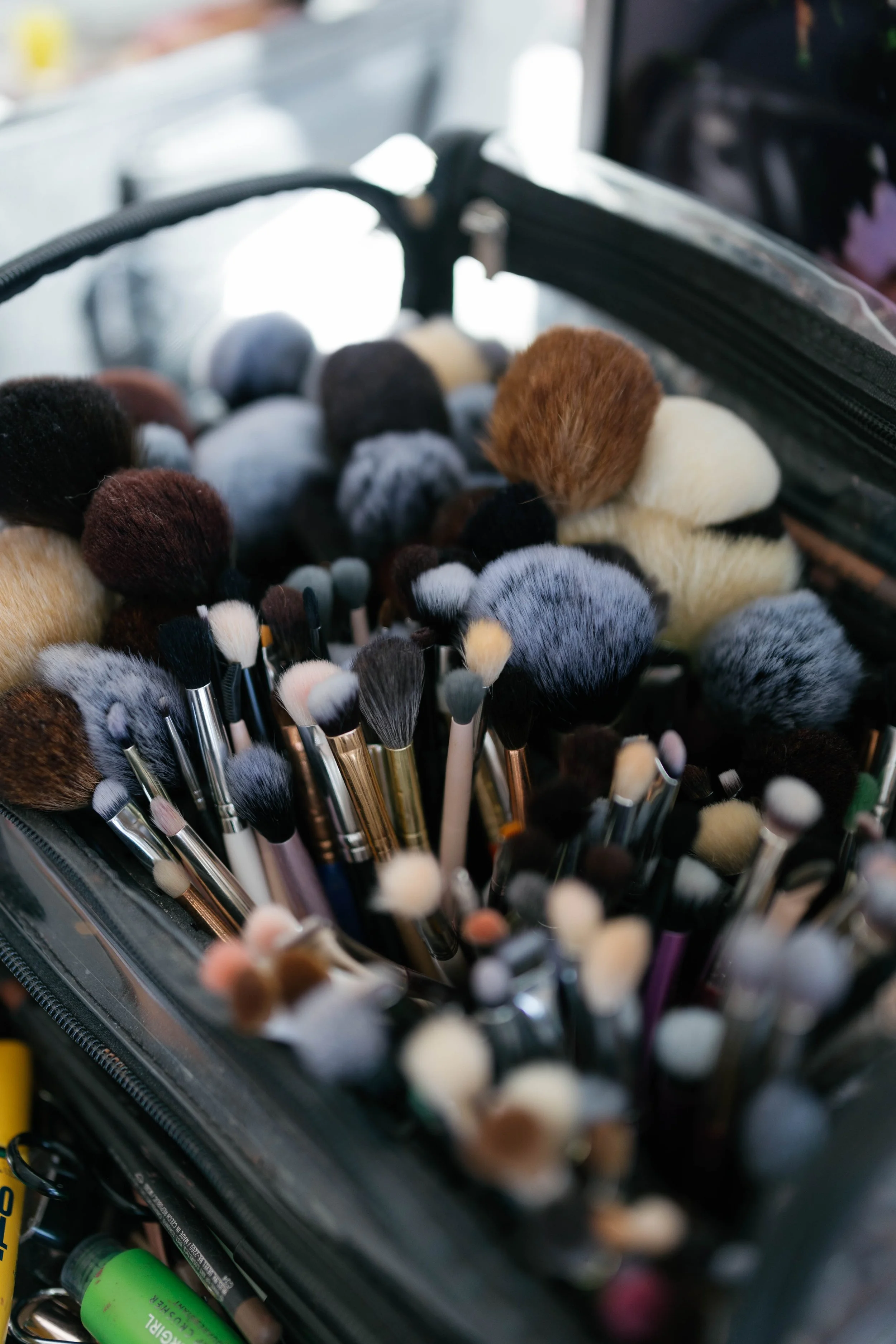 Close-up of a collection of makeup brushes and tools inside a clear case.