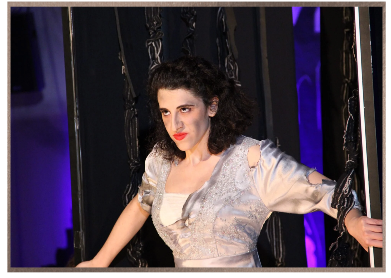 Adi Denner backstage within a theatrical set during an opera production.