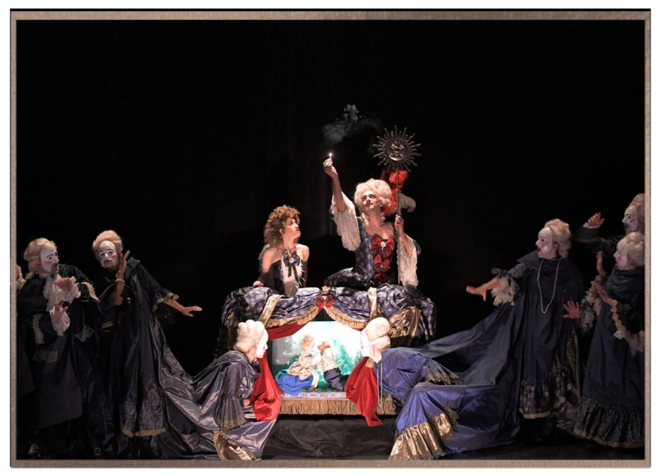 Adi Denner performing in an opera production surrounded by a costumed ensemble.