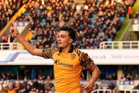 Soccer player in yellow and black jersey celebrating on the field with a crowd in the background.
