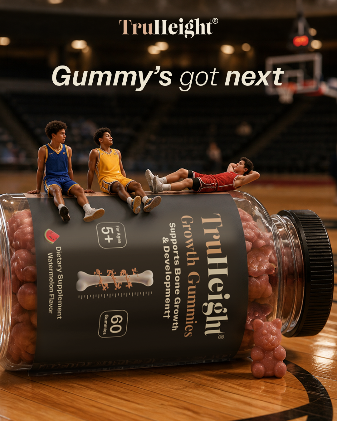 A large bottle of gummy vitamins lying on a basketball court floor, with three tiny basketball players on top of it, one of whom is lying down and two sitting.