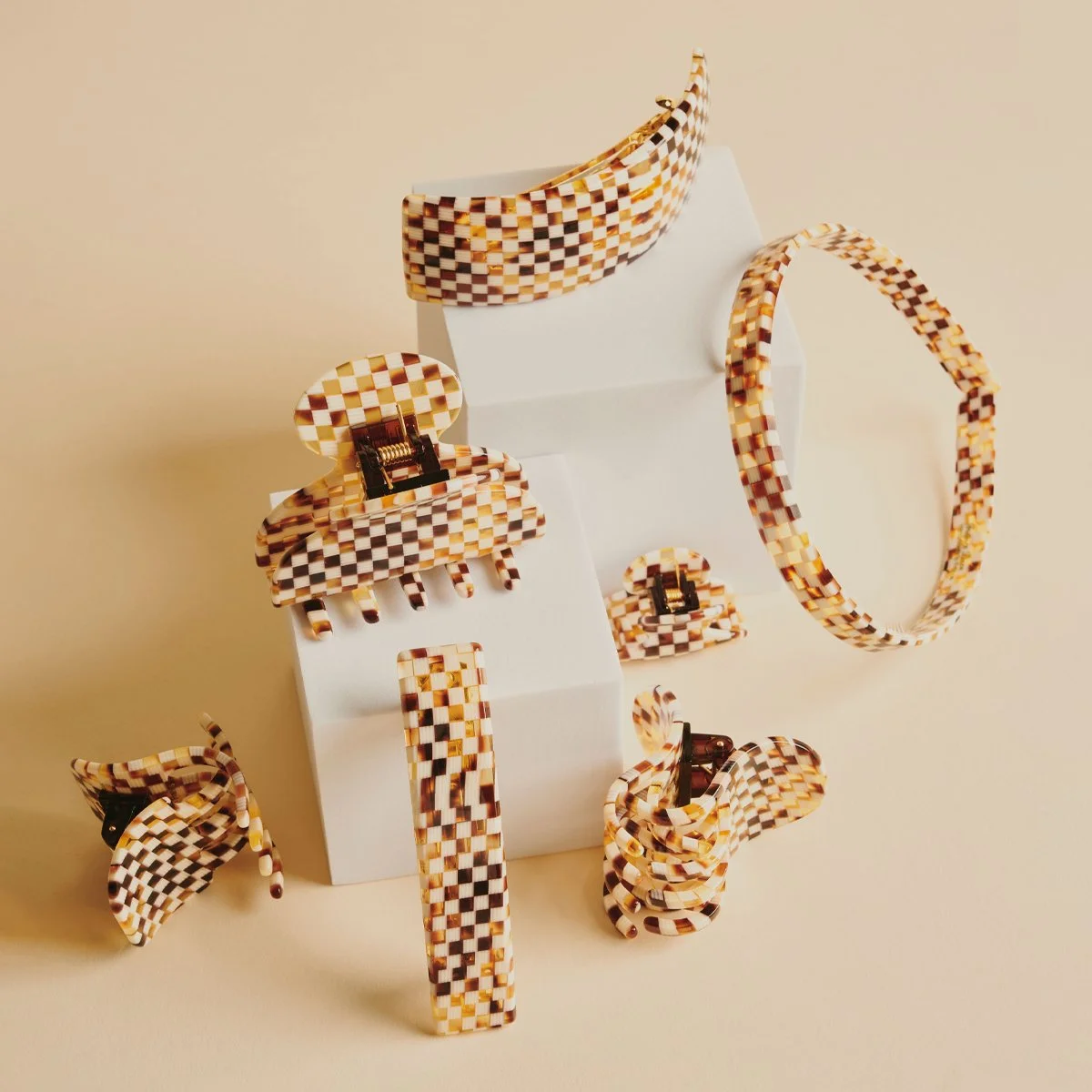 Set of matching checkered jewelry accessories including a choker, hoop earrings, a hair clip, a bangle, and two rings displayed on white blocks.