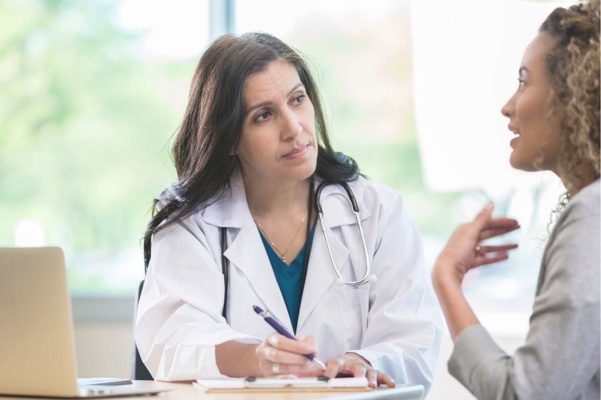 Doctor talking to a patient at a desk while taking notes.
