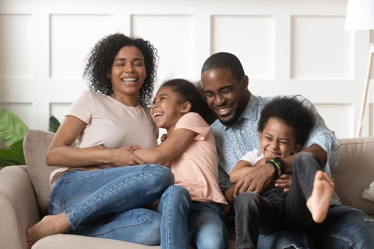 Family sitting together on a couch while laughing.