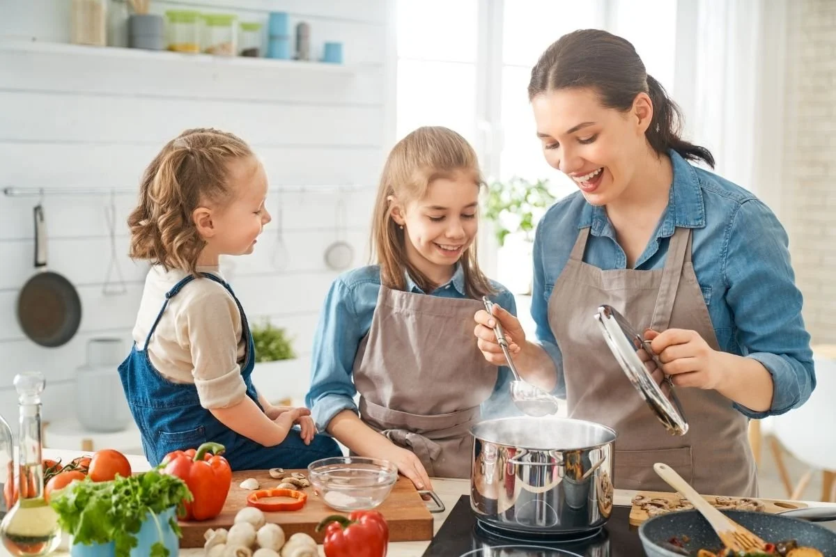 Mother and two young daughters cooking dinner together.
