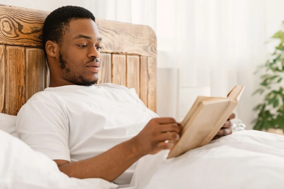 Man reading book in bed.