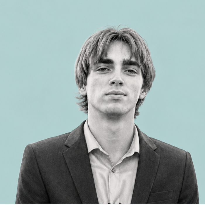 Black-and-white portrait of a young man with medium-length hair, wearing a suit jacket and shirt, against a light teal background.