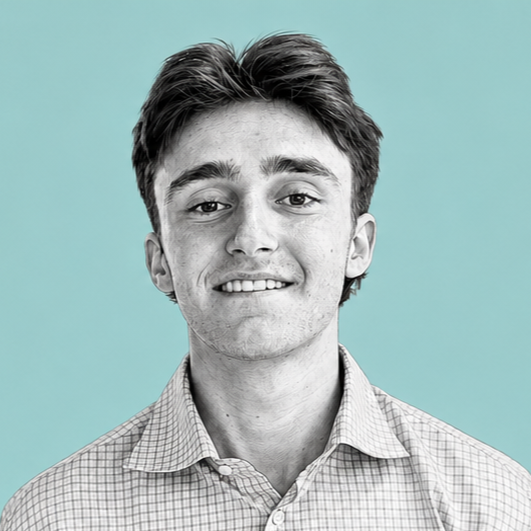 Portrait of a young man with brown hair, smiling, wearing a checkered shirt, against a light blue background.
