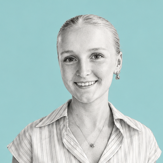 Portrait of a smiling woman with slicked-back hair, wearing a striped collared shirt and jewelry, against a solid light blue background.