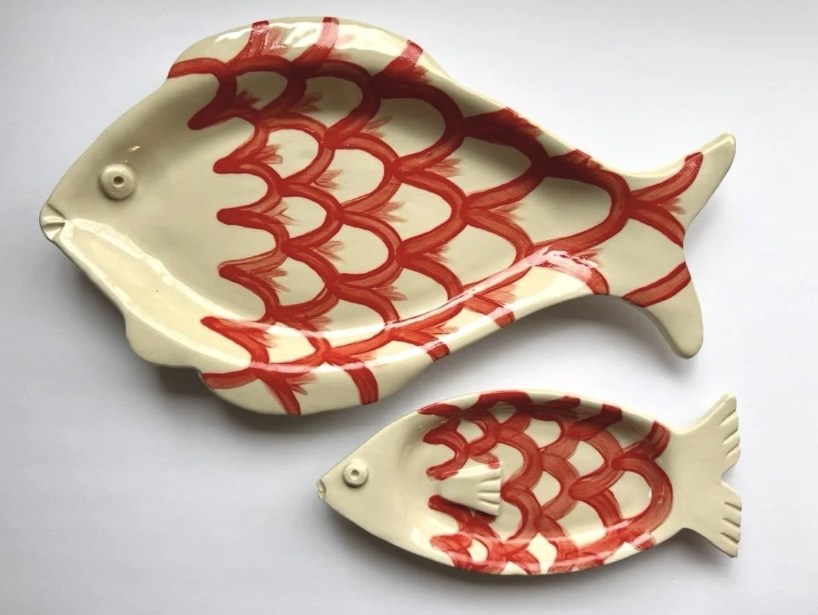 Two fish-shaped ceramic dishes with red fish scale patterns, one larger and one smaller.