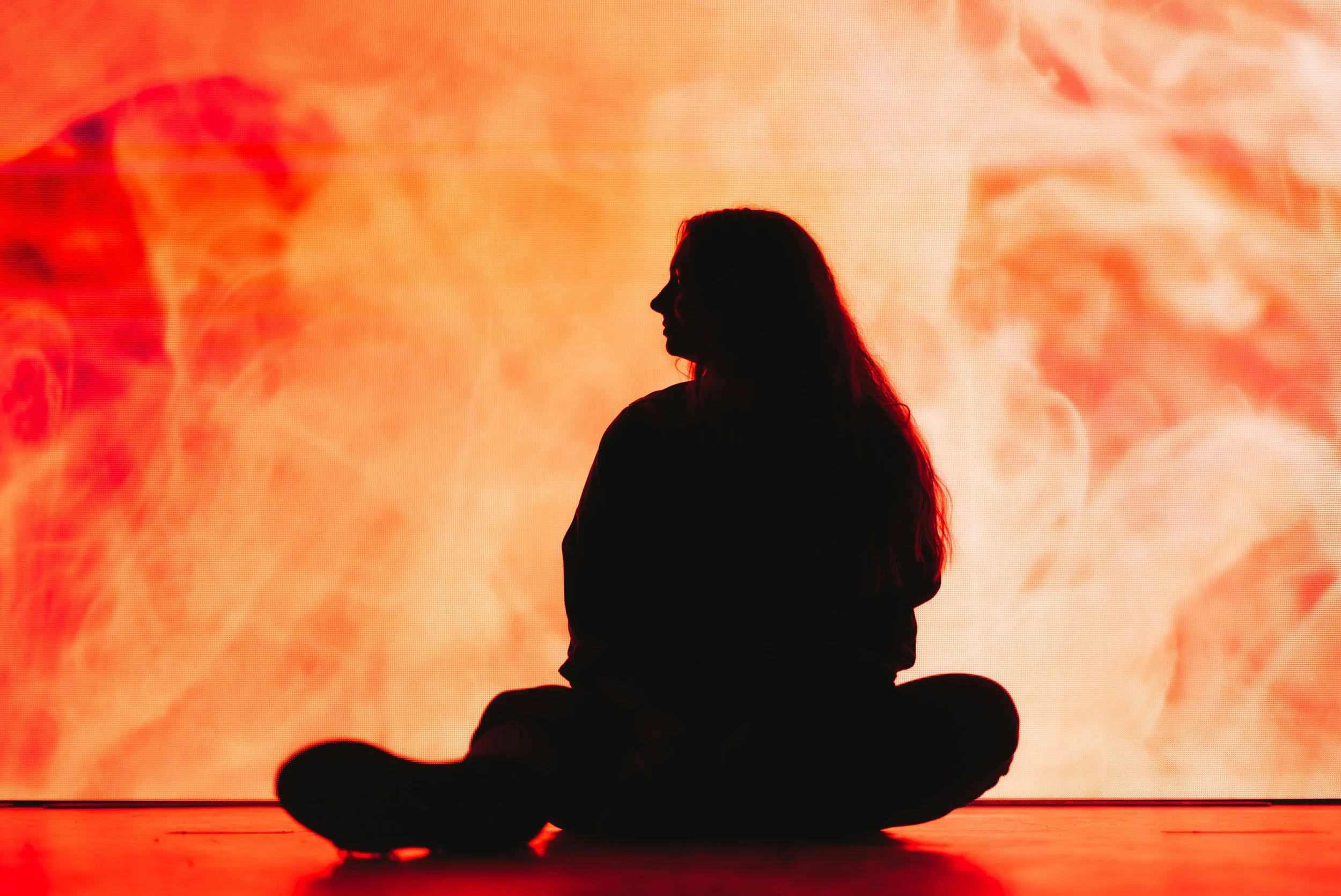 Silhouette of a person sitting in a meditative pose with a fiery, swirling background.