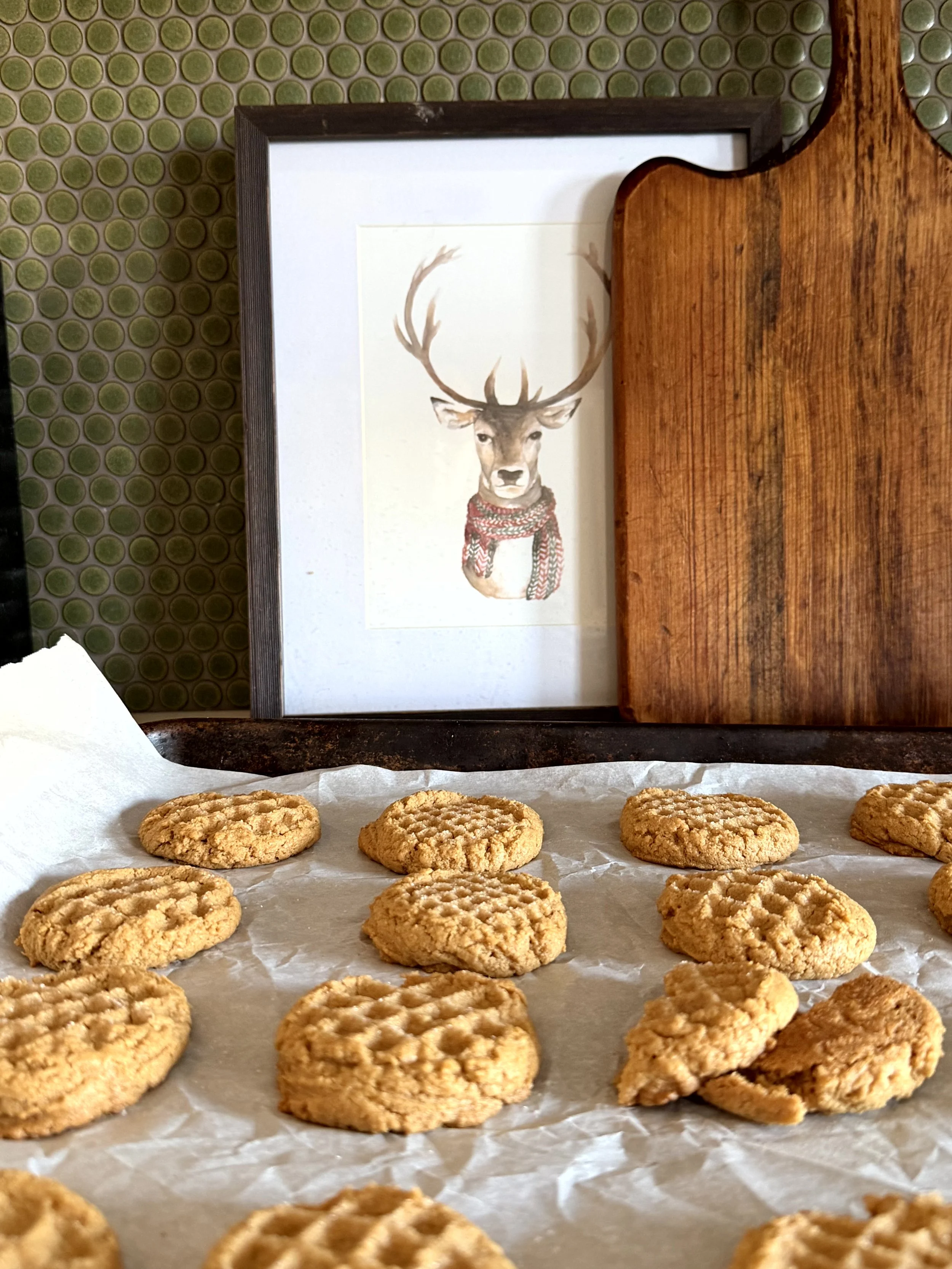 peanut butter cookies, on a parchment lined cookie sheet, in a cozy kitchen decorated for christmas