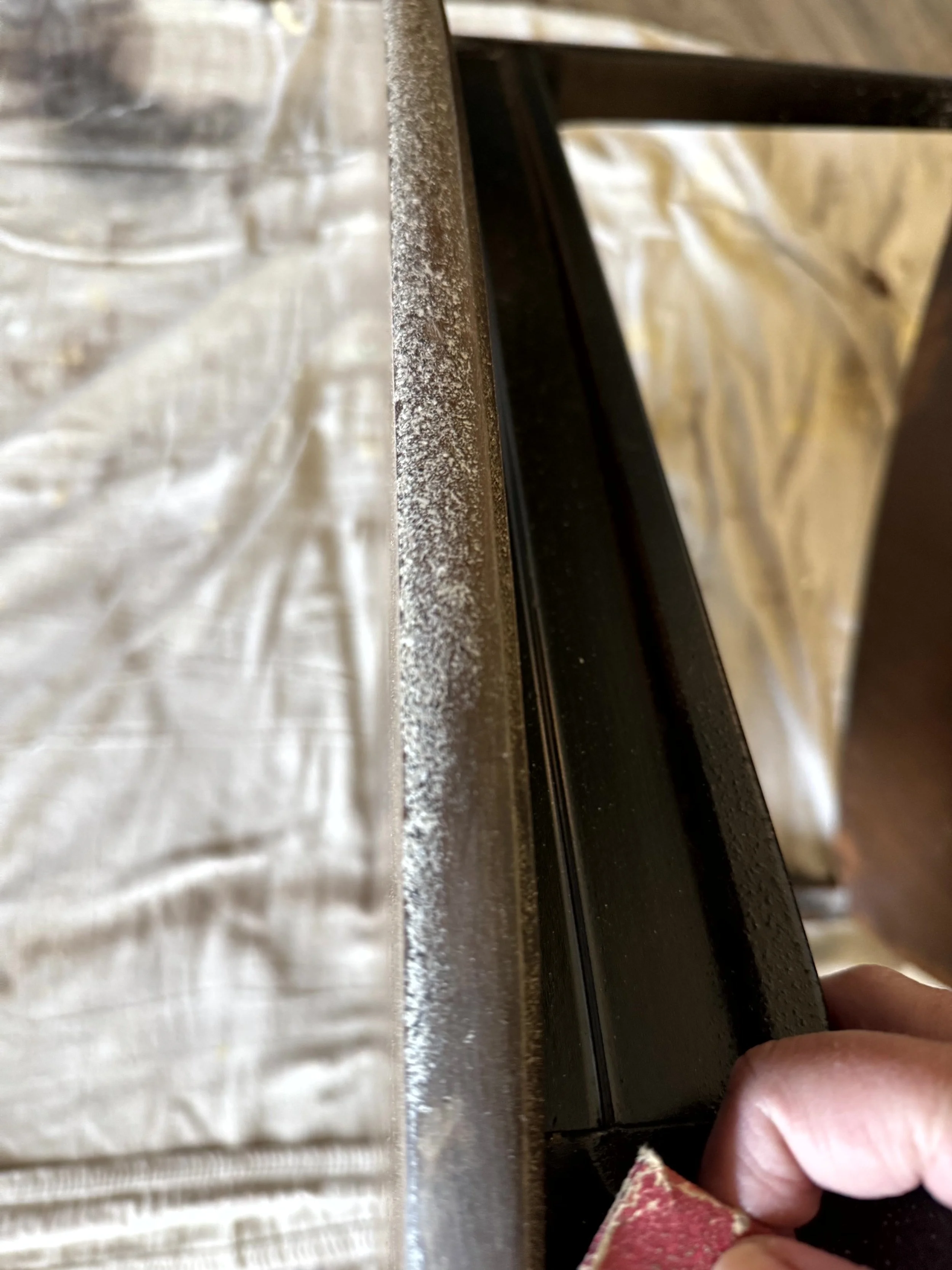  A close up shot of a mid century modern triangle table that a woman is sanding down to get the paint off of. This table has been a work in progress but little by little she is bringing it back to life.  