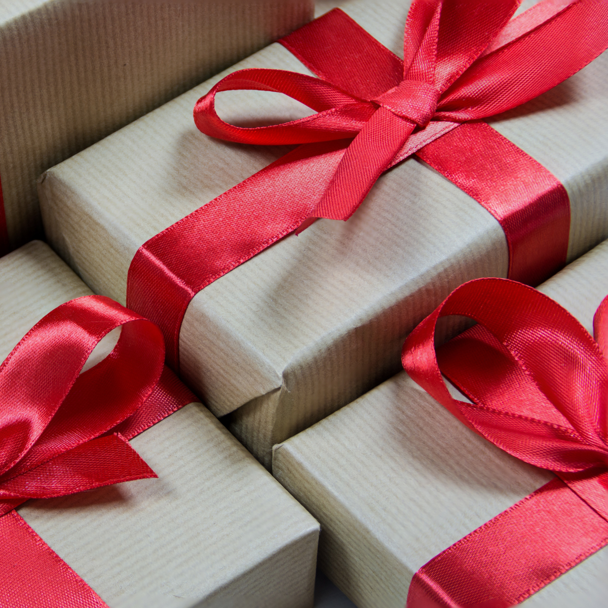 Close-up of beige gift boxes wrapped with red satin ribbons, decorated for a celebration.