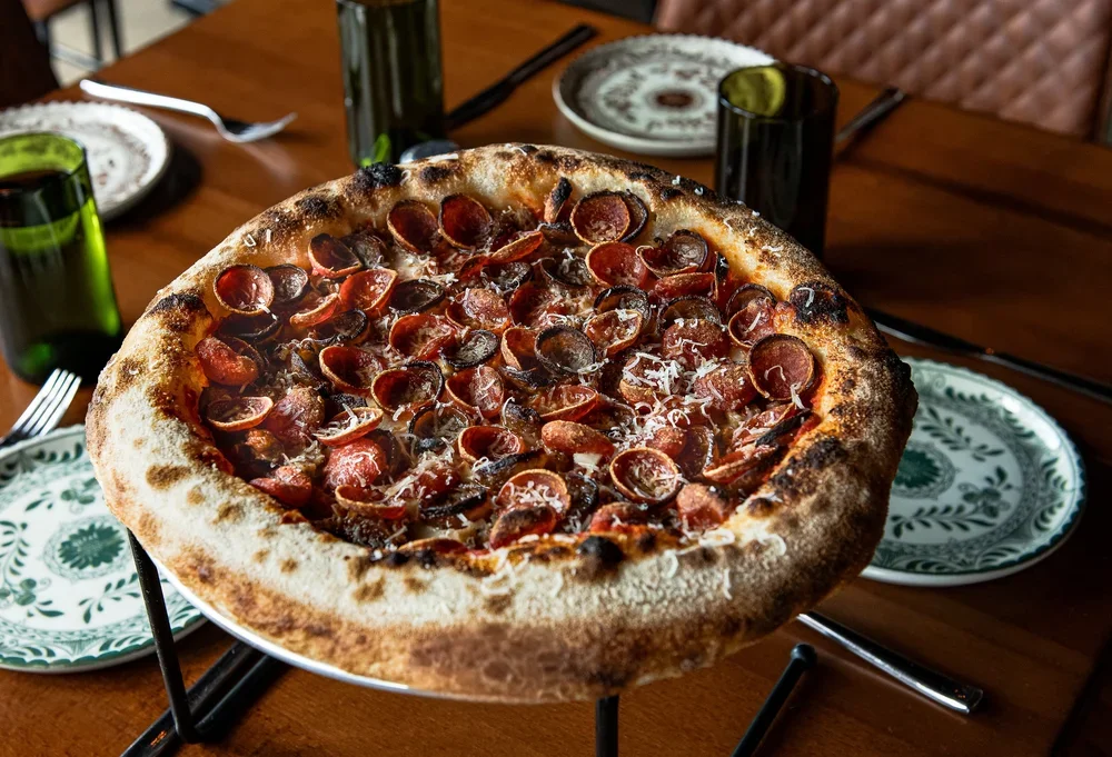 Pizza with pepperoni and cheese on a table set for dinner.
