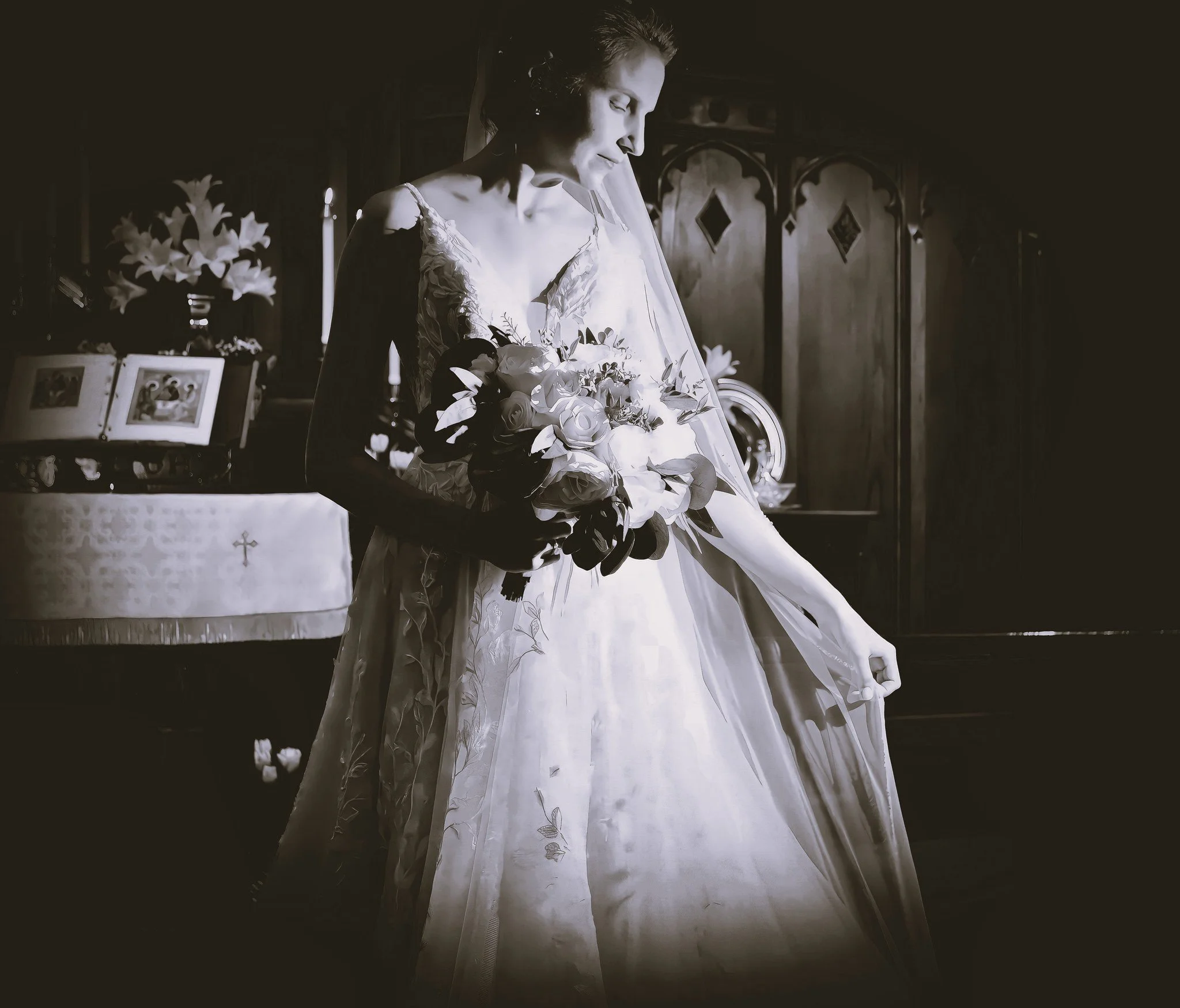 A bride in a wedding dress holding a bouquet of flowers in a church, with a dark wooden background and framed pictures on a table.