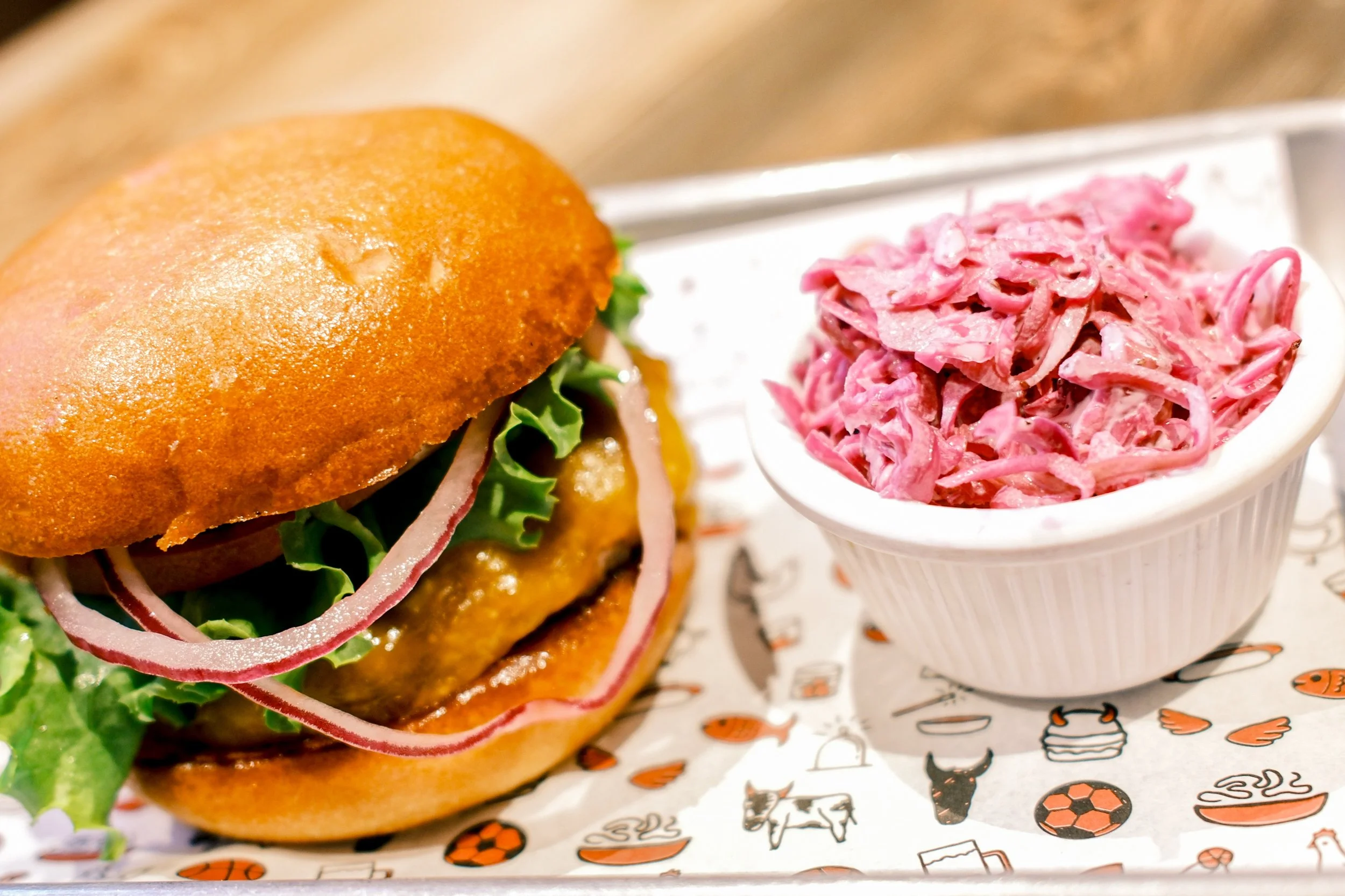 A close-up of a cheeseburger and coleslaw at Hamburguesía, a Costa Rican better-burger restaurant, by OLA Creative Studio