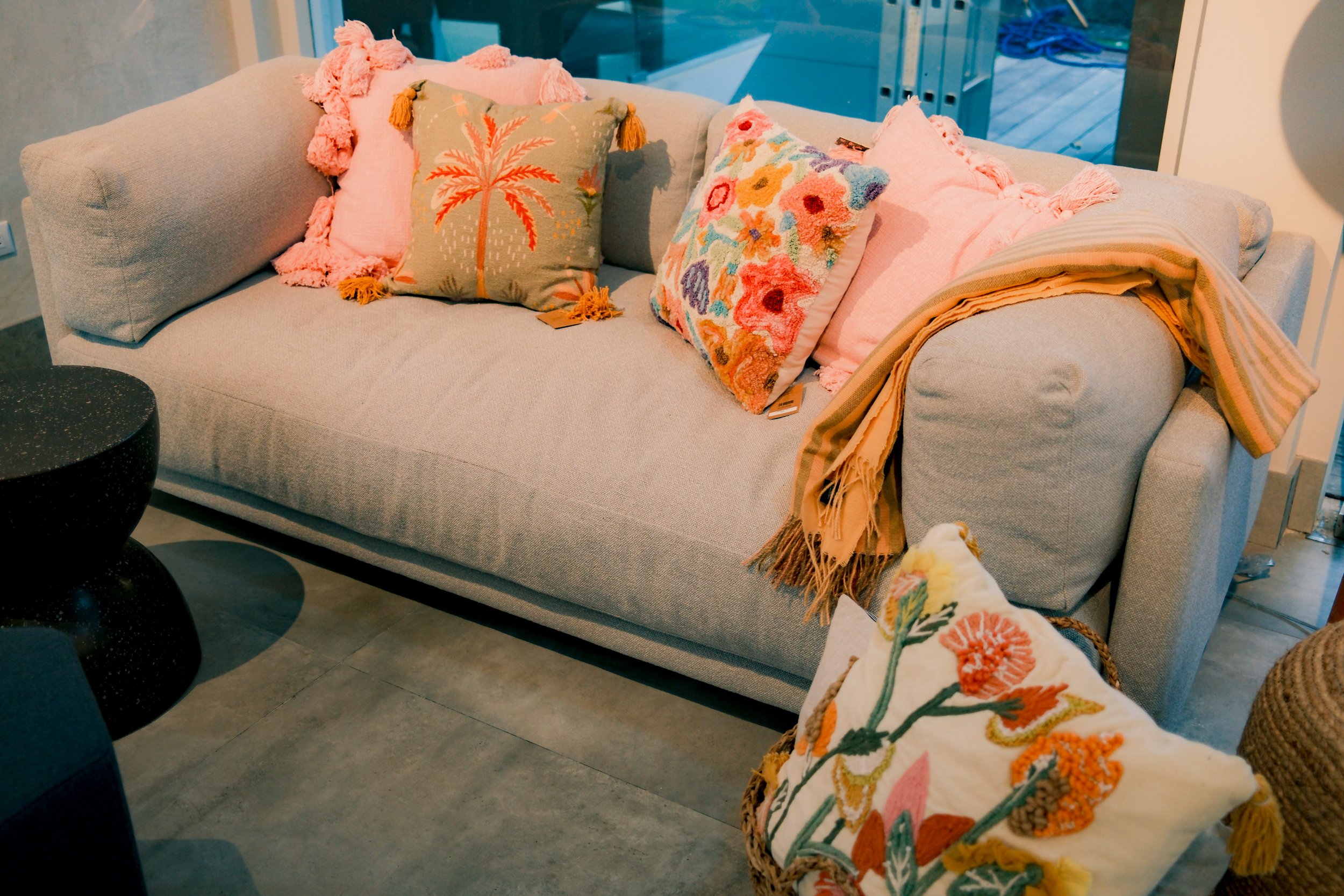 A styled sofa with embroidered pillows and a striped throw at Mad Living, a Costa Rican furniture brand, by OLA Creative Studio