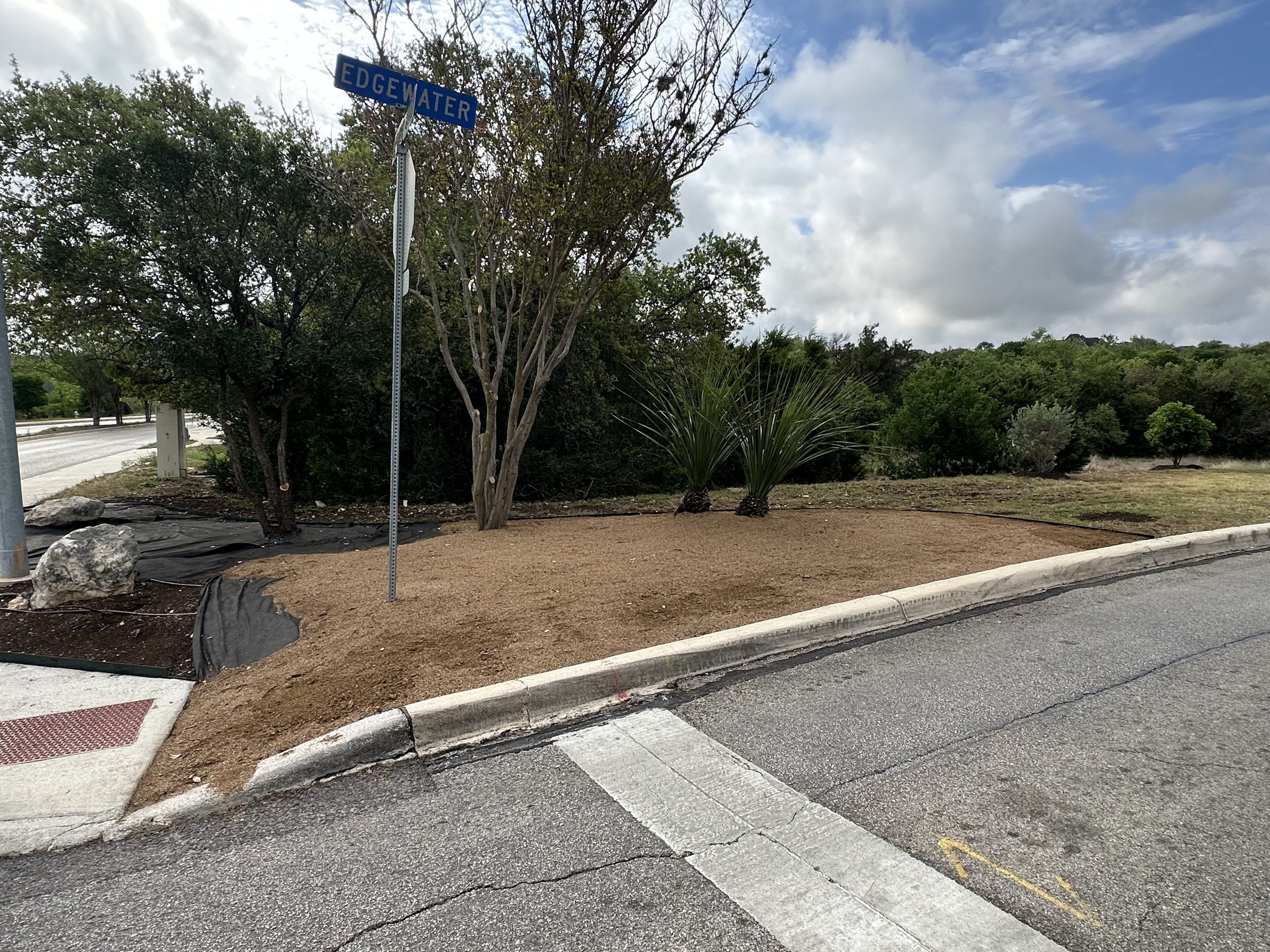 Bare entrance corner bed before xeriscape installation at the Heights at Stone Oak