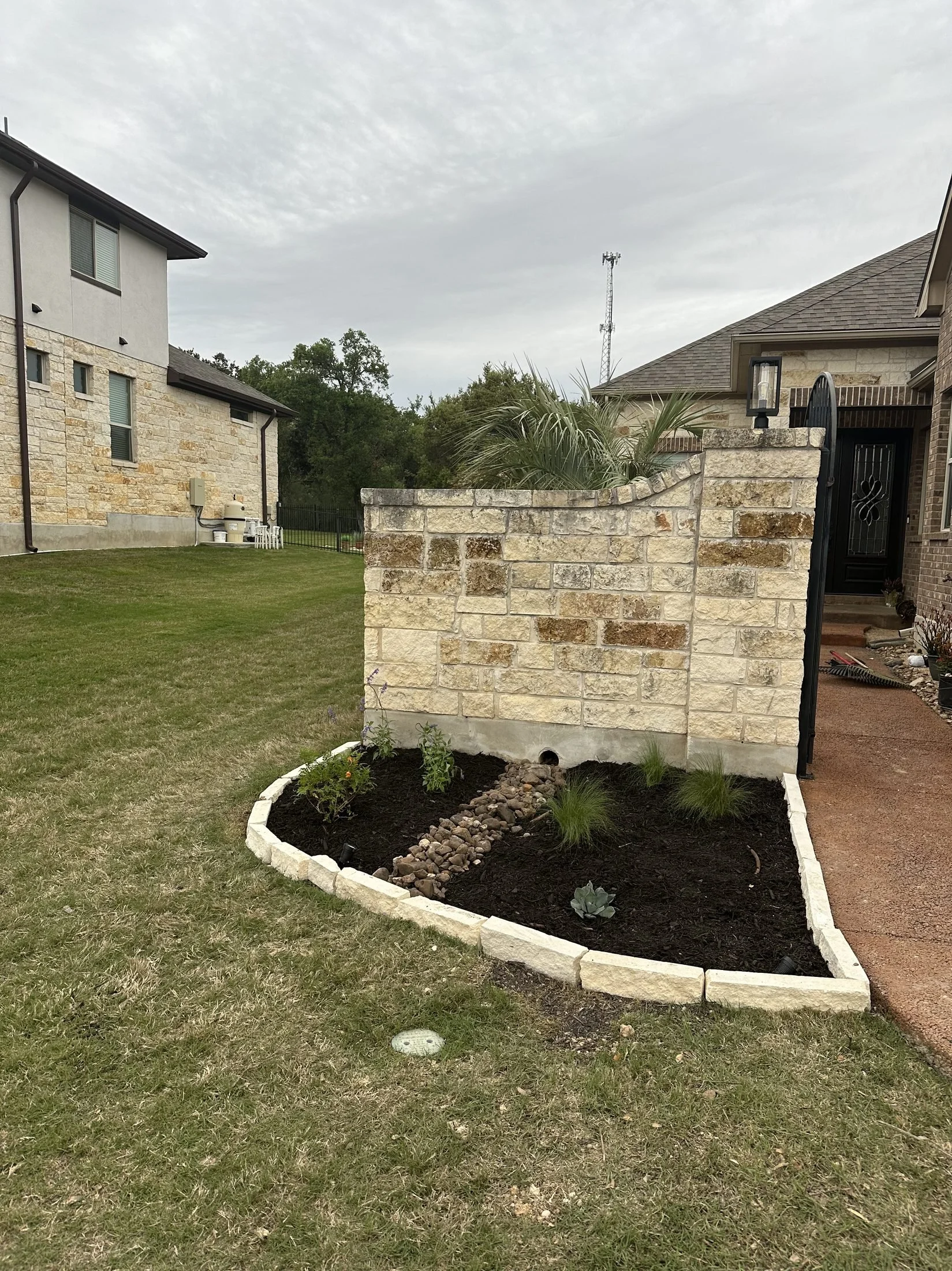 Stacked stone wall with creek bed look at a Central Texas yard