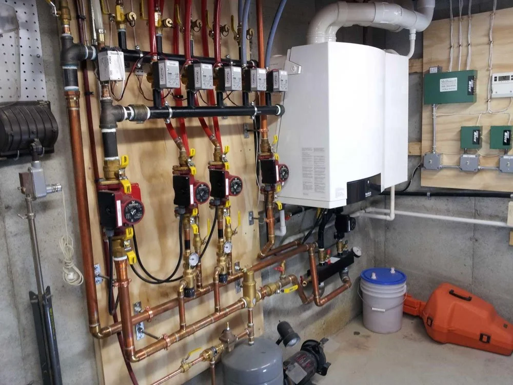 A boiler system with control units, pipes, gauges, and pumps in a utility room.
