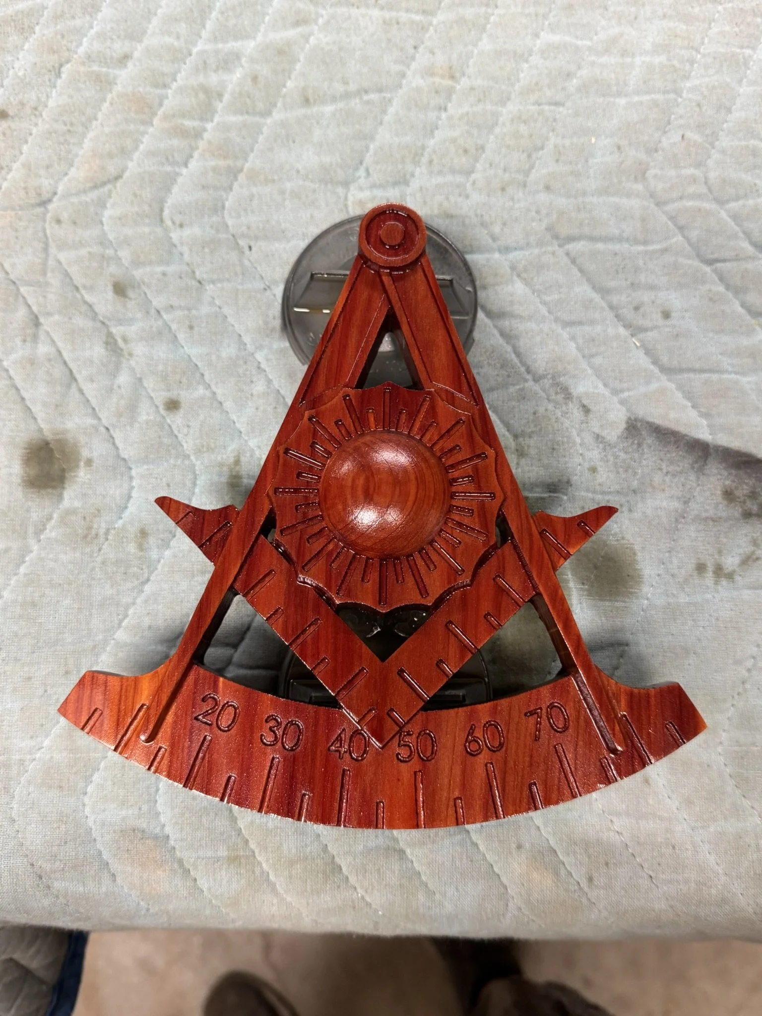 Top view of a wooden outdoor thermometer with a decorative sun design, mounted on a light-colored surface.