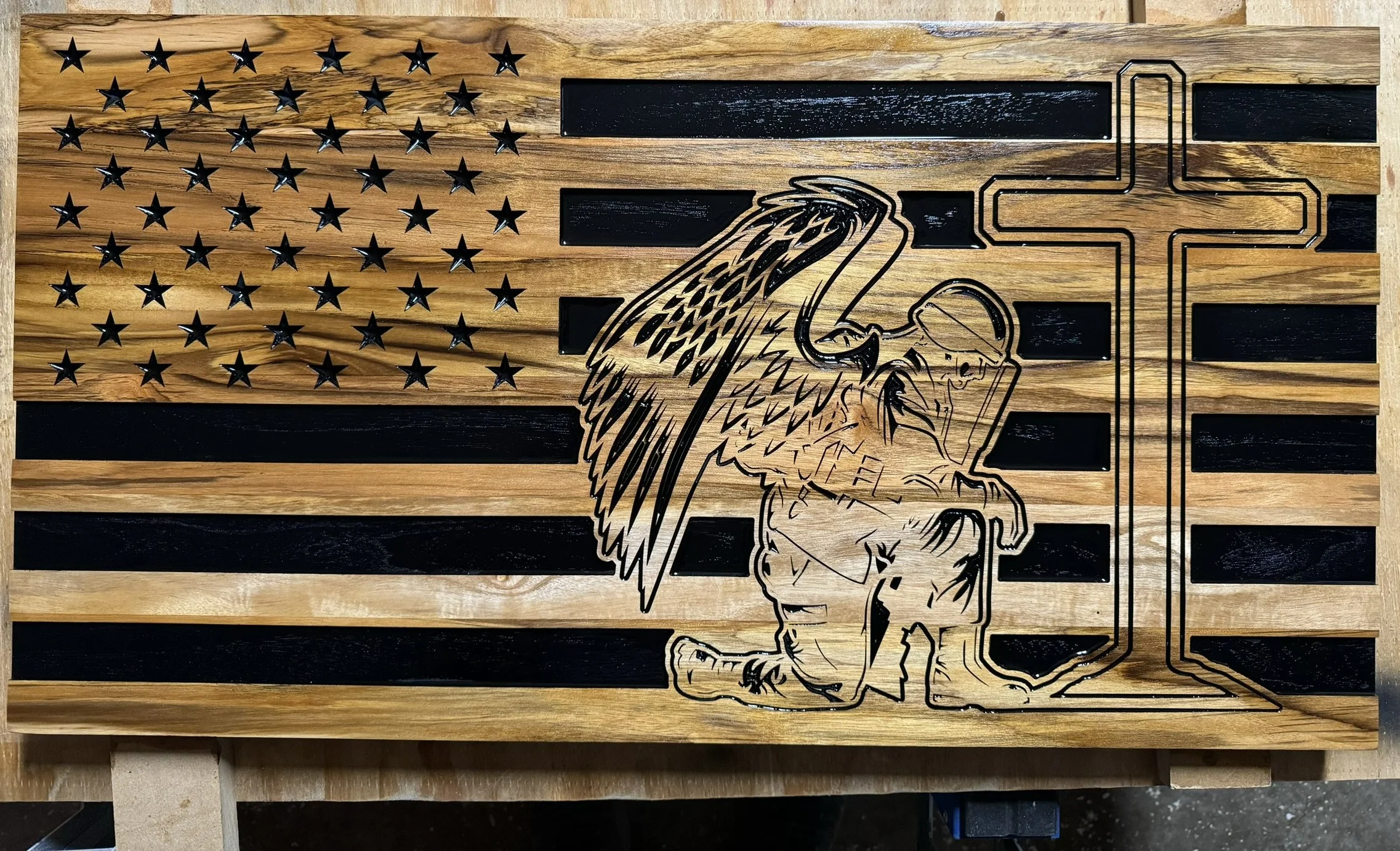 Wooden American flag with black stars and stripes, featuring a metal Liberty Bell and an outline of a firefighter's helmet with a badge.