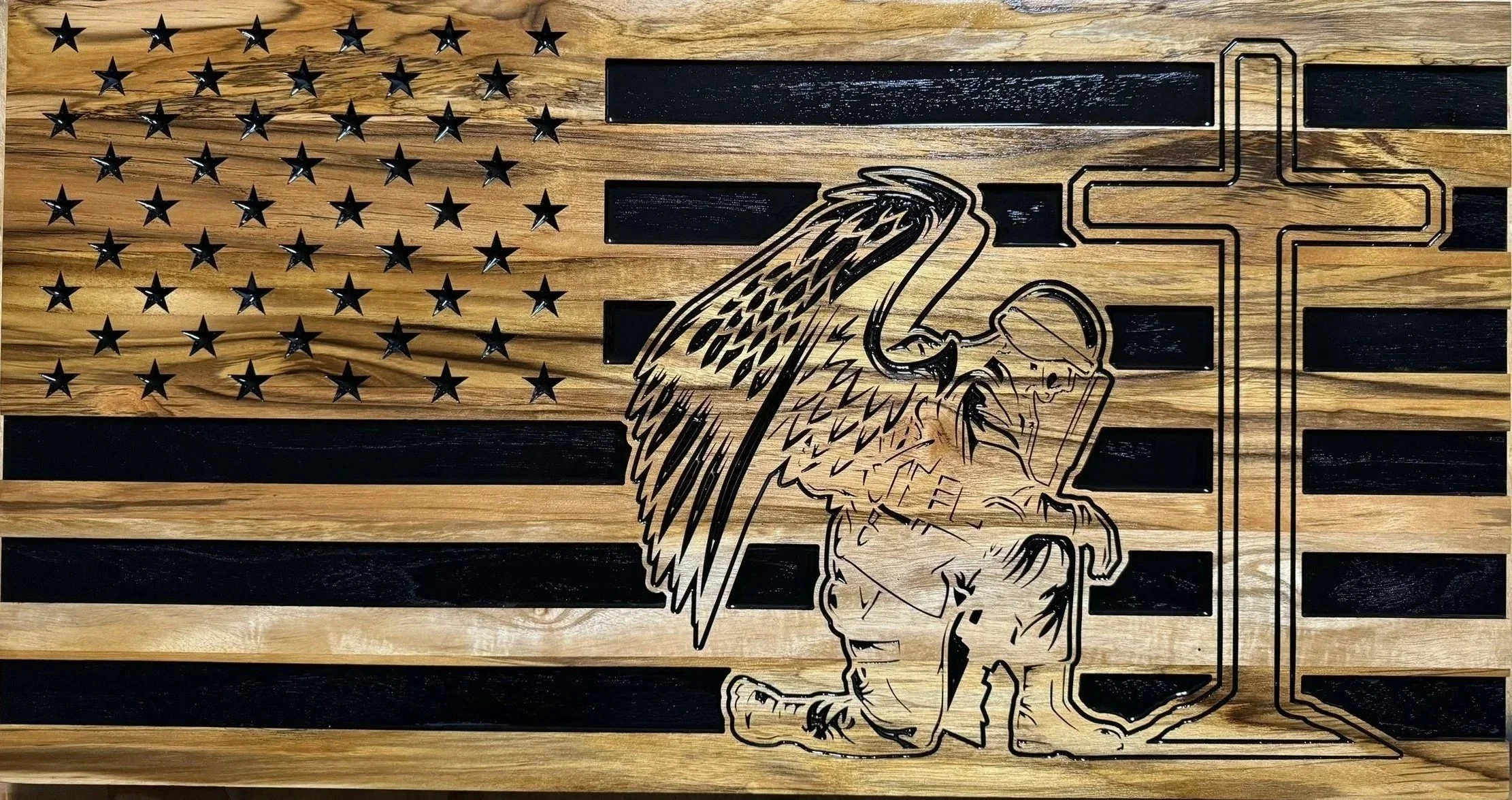 A wooden American flag with black and natural wood stripes, black stars, and a black outline of a soldier saluting with an eagle's head and wings incorporated into the flag design.