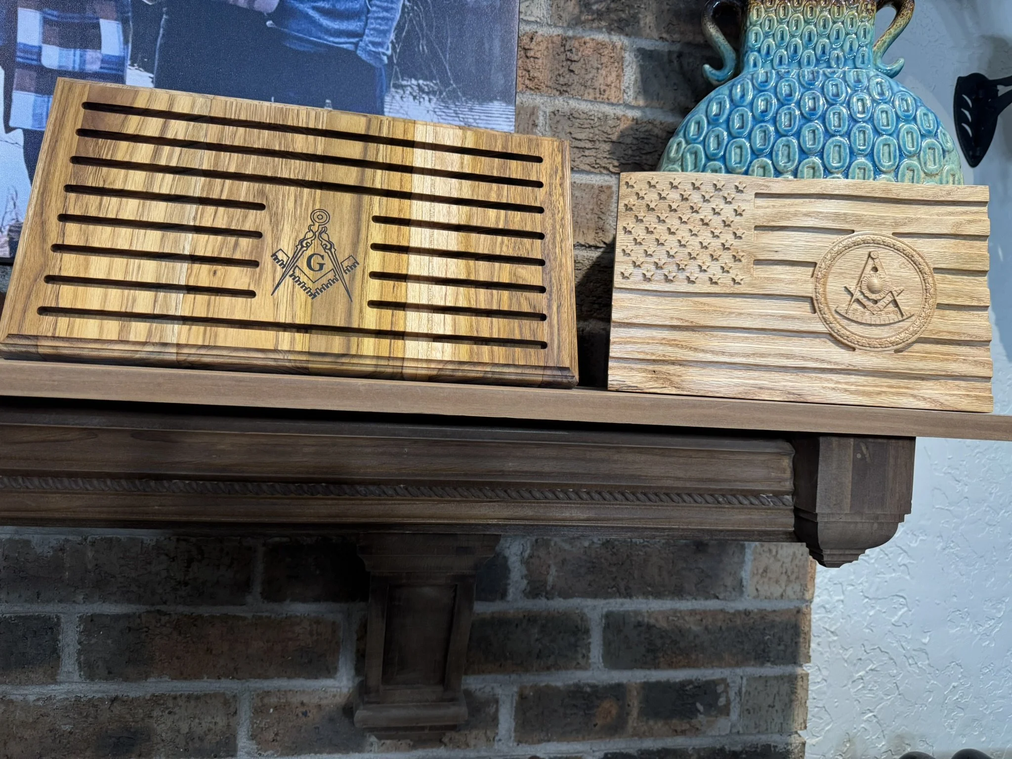 Two wooden beer crates with slatted tops and an emblem, placed on a brick ledge next to a decorative blue-green ceramic vase.