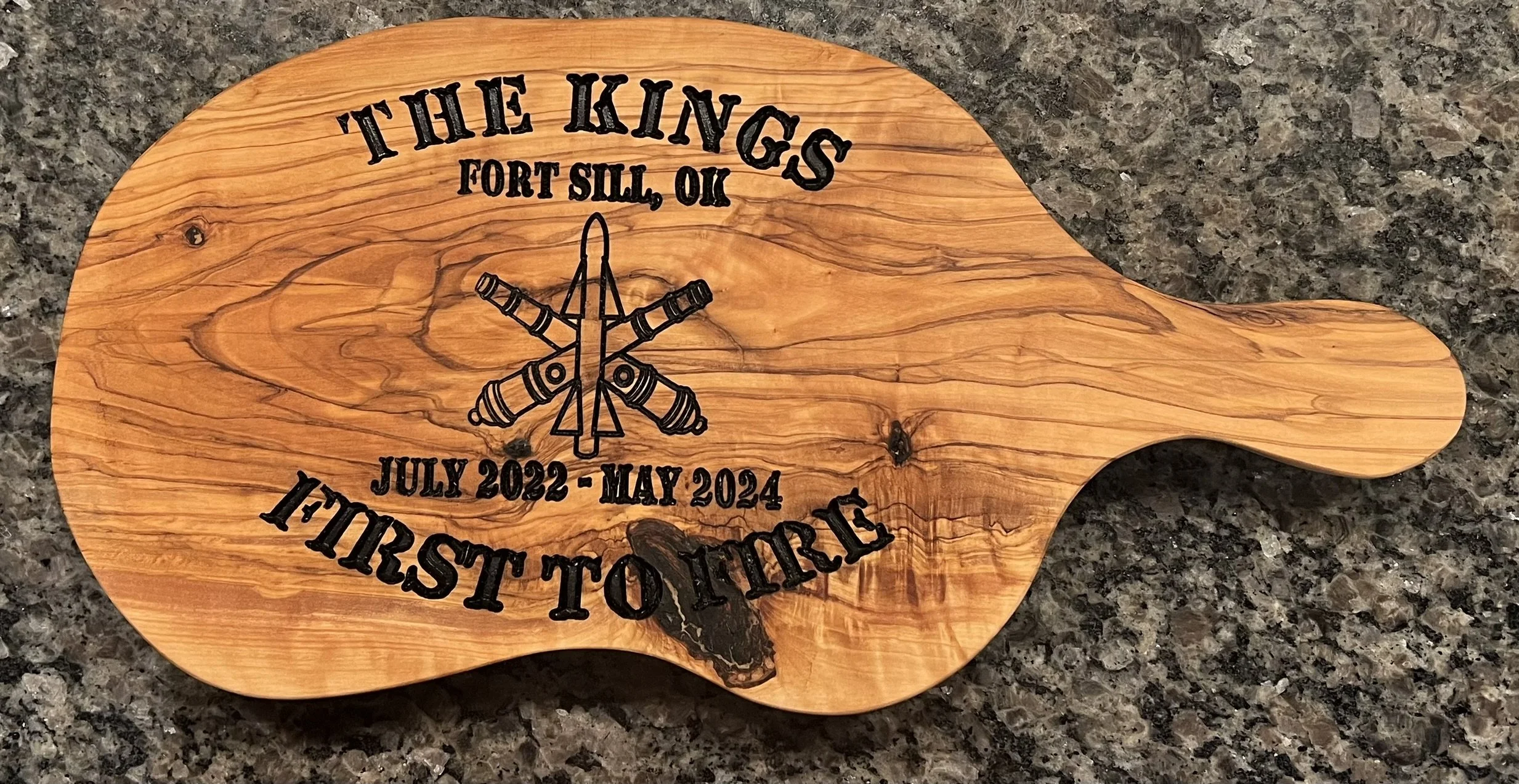 Wooden cutting board with engraved text 'The Kings, Fort Sill, OK, July 2022 - May 2024, 1st Battalion, 19th Infantry Regiment', and an illustration of crossed rifles.