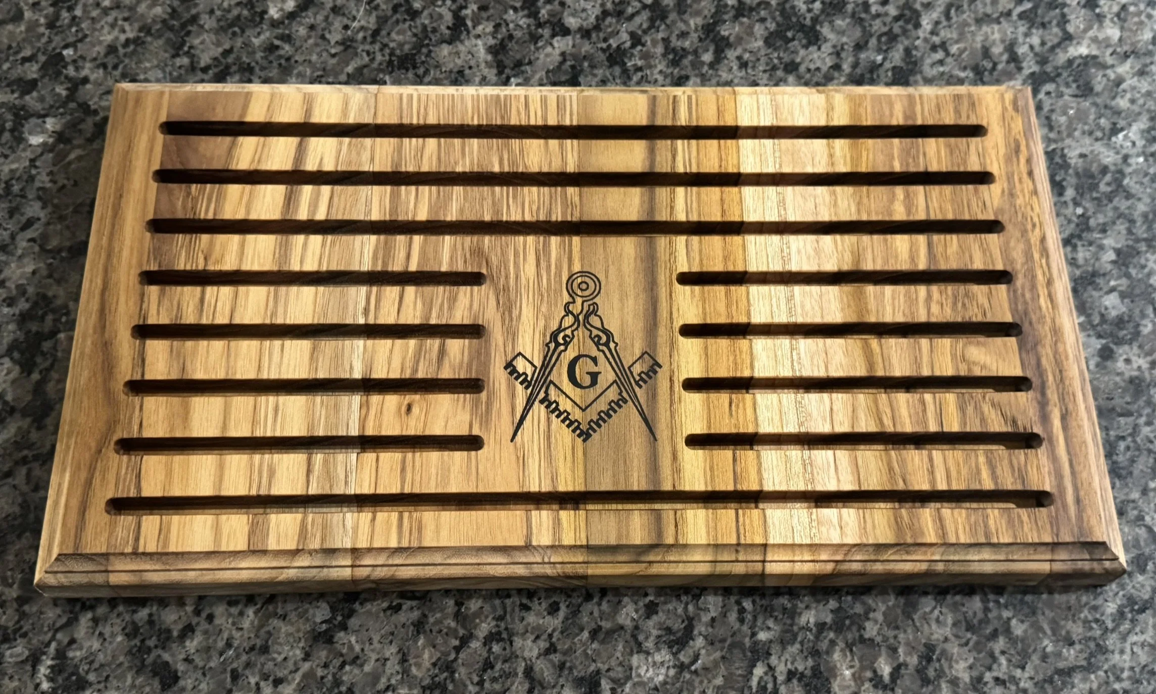 A wooden chess or checkers board with ten rows of horizontal slots, with a Masonic symbol in the center.